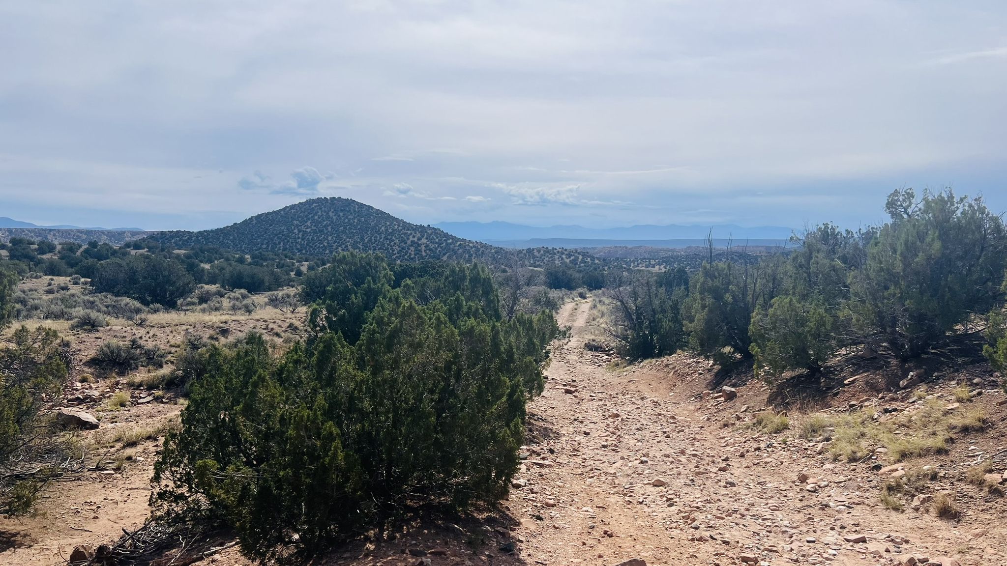 Dirt road winding through arid landscape under a cloudy sky. - Joseph’s Mine Trail