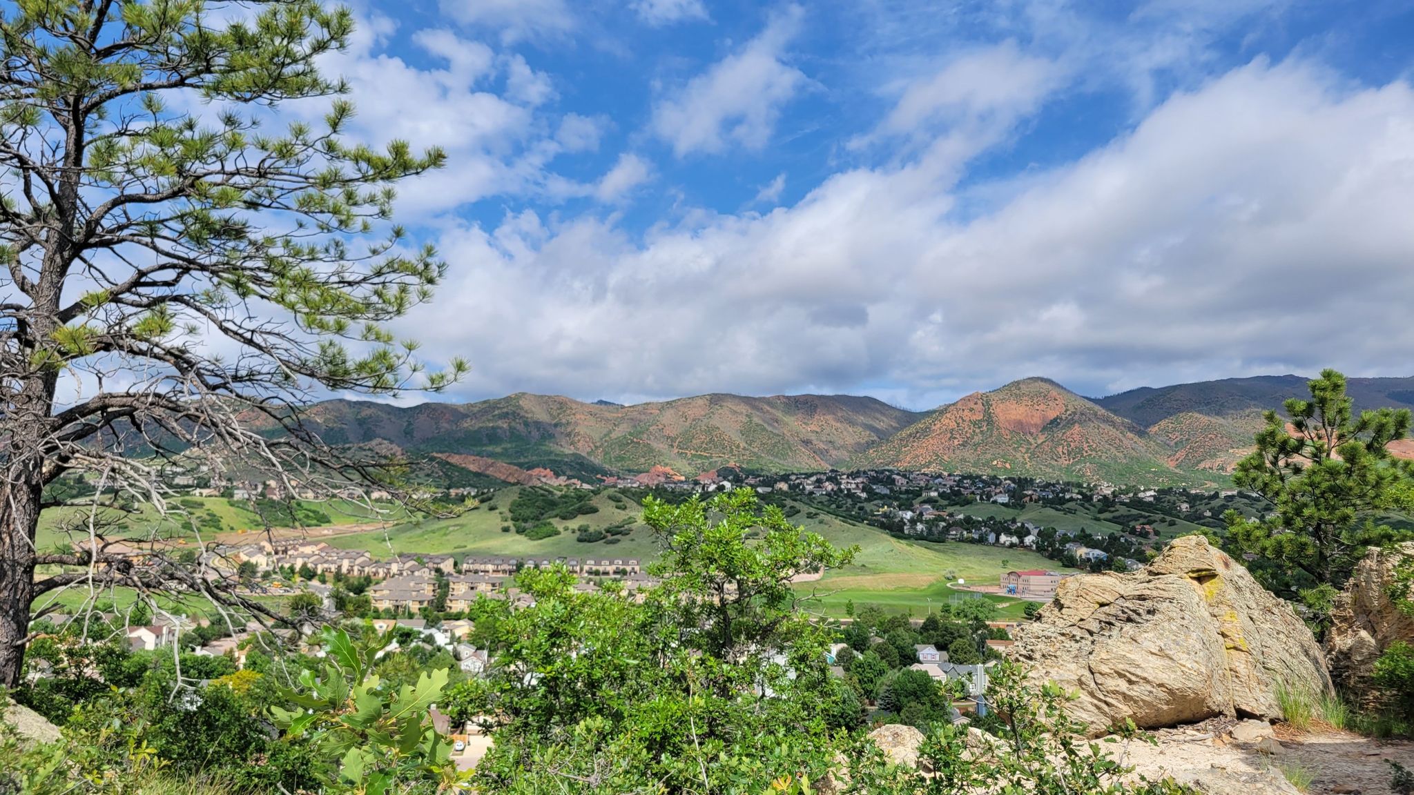 Mountainous landscape with a valley town under a partly cloudy sky. - View of Ute Valley Park – View of Ute Valley Park loop from Ute Valley Park