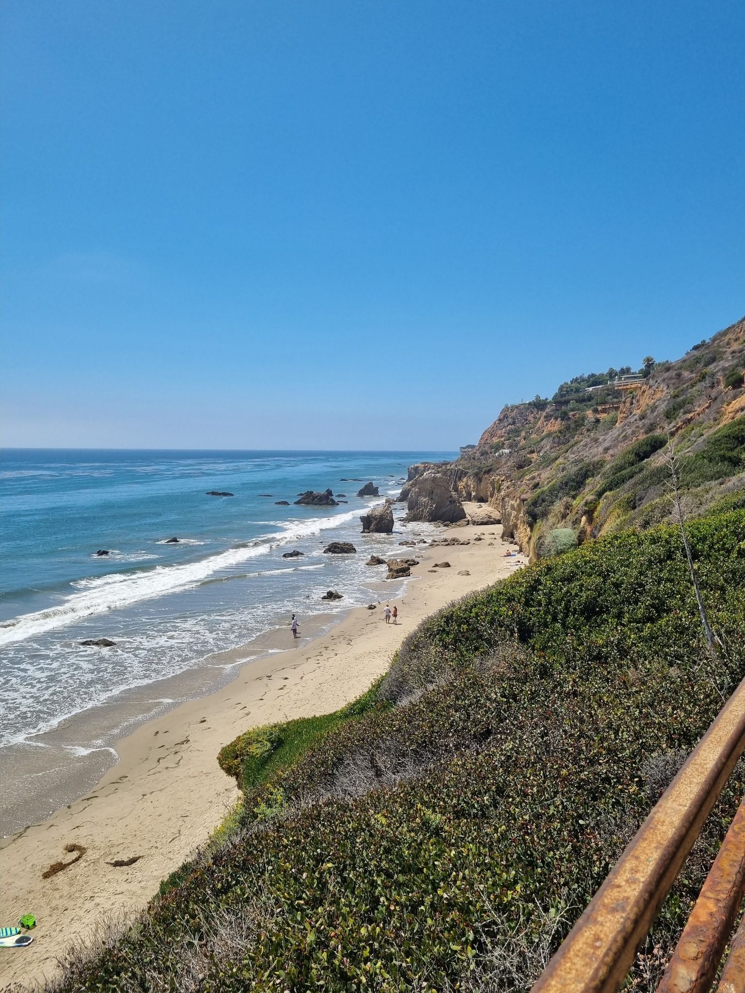 Elevated view of a sunny beach, ocean waves, and rocky cliffs with people. - El Matador, La Piedra and El Pescador State Beaches