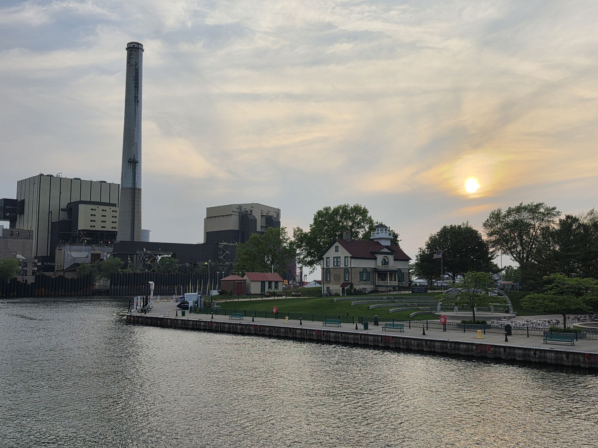 Industrial building and house by water at sunset with people on pier. - La Porte & Red Mill County Park loop from Michigan City