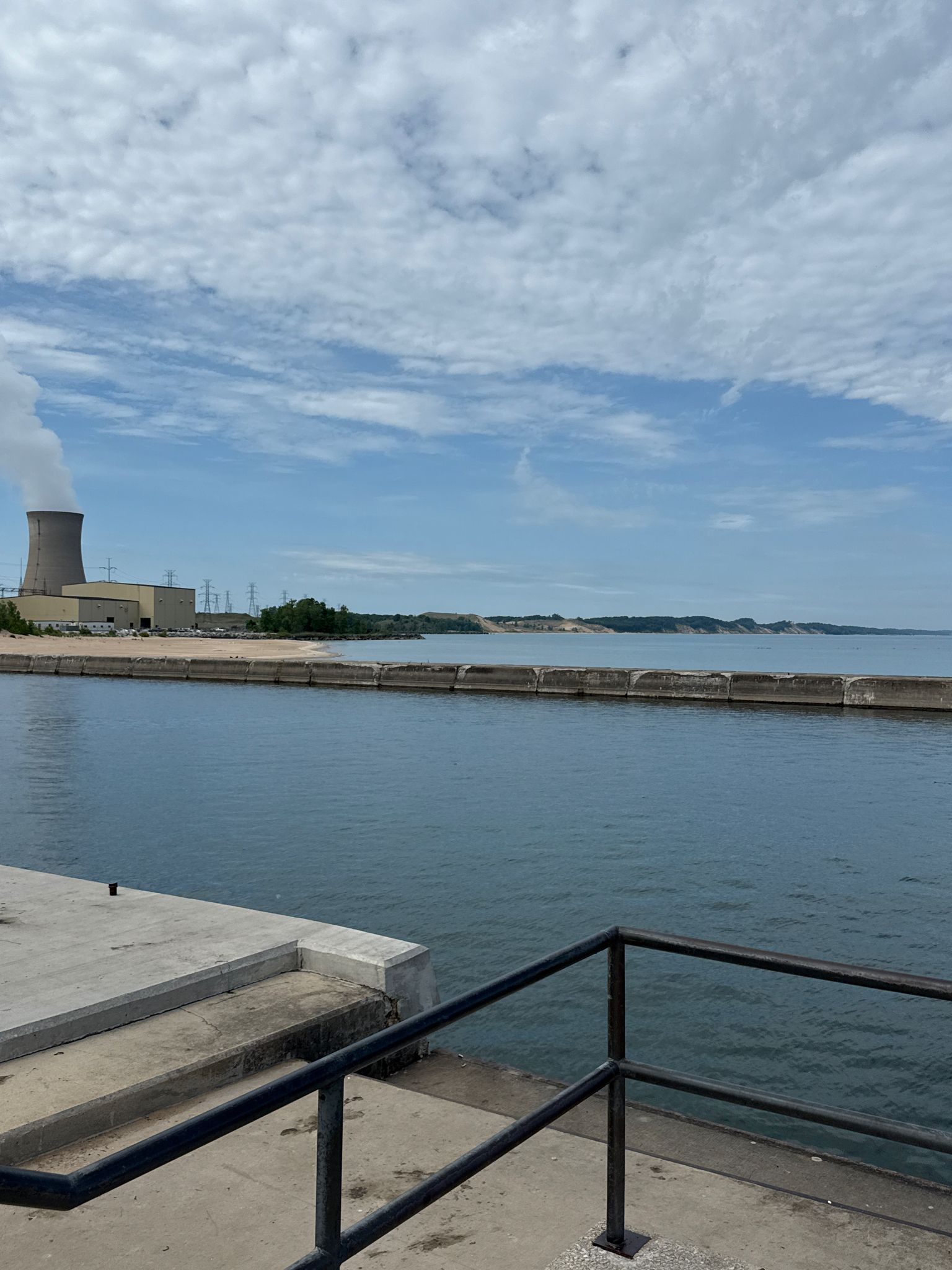 Waterfront view with an industrial building and distant sandy hills. - Mount Baldy to Long Beach Trail
