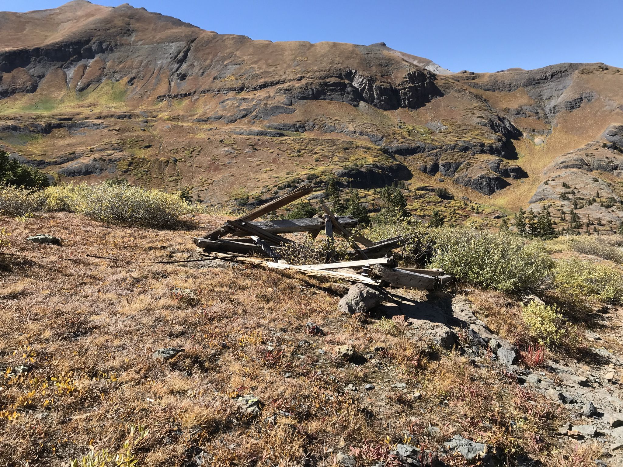 Weathered wooden debris on a dry, grassy mountain slope under bright sun. - Blue Lake via Bridal Veil Trail