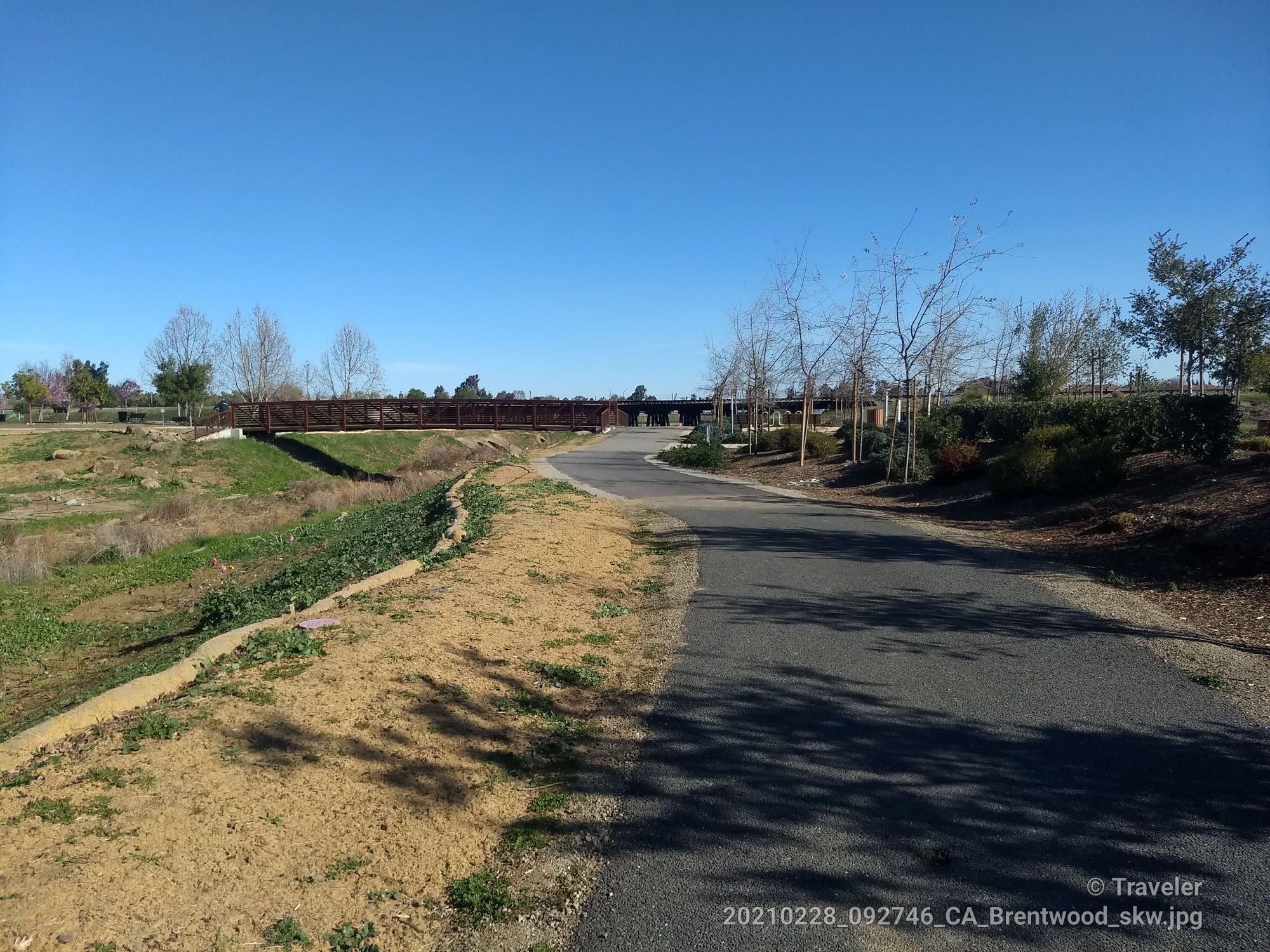 Paved path curving towards a distant bridge, dry grass, clear blue sky. - Vineyard Climb – Kestrel Park loop from Brentwood