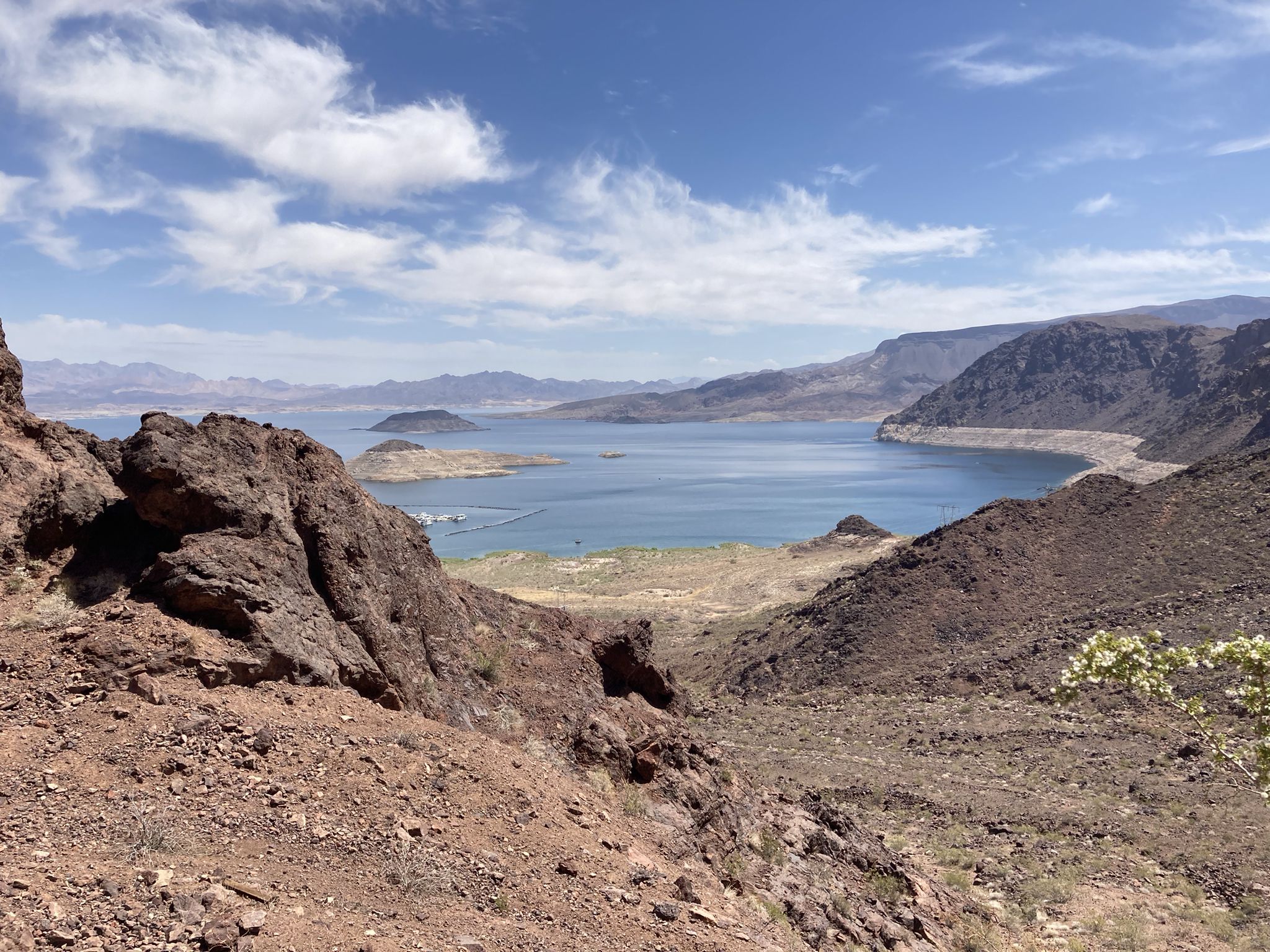 Expansive blue lake nestled among rugged, arid mountains under a partly cloudy sky. - Railroad Tunnel Trail