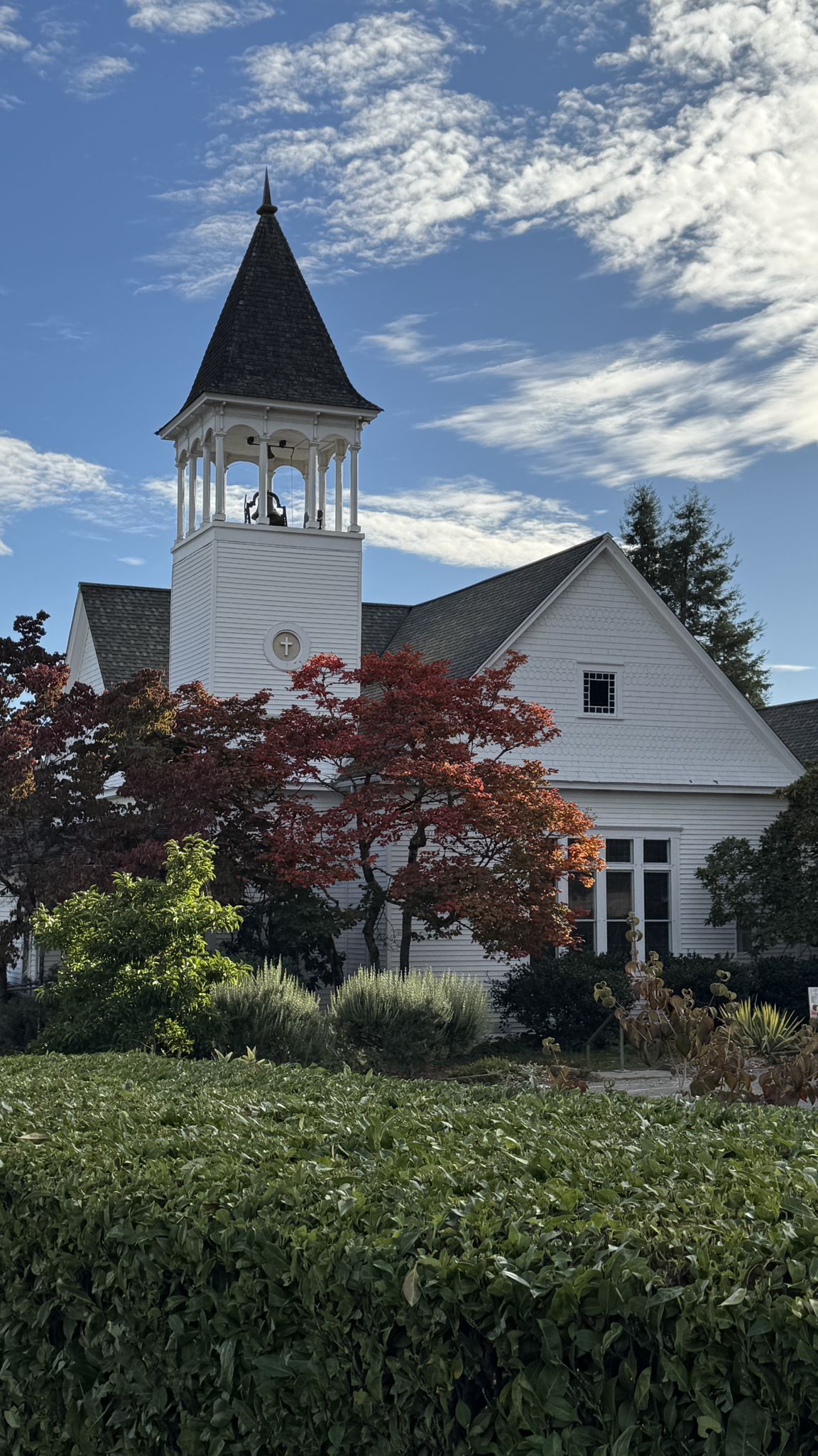 White church with a bell tower, autumn trees, and blue sky. - Bird's Nest loop from Bainbridge Island Japanese American Exclusion Memorial