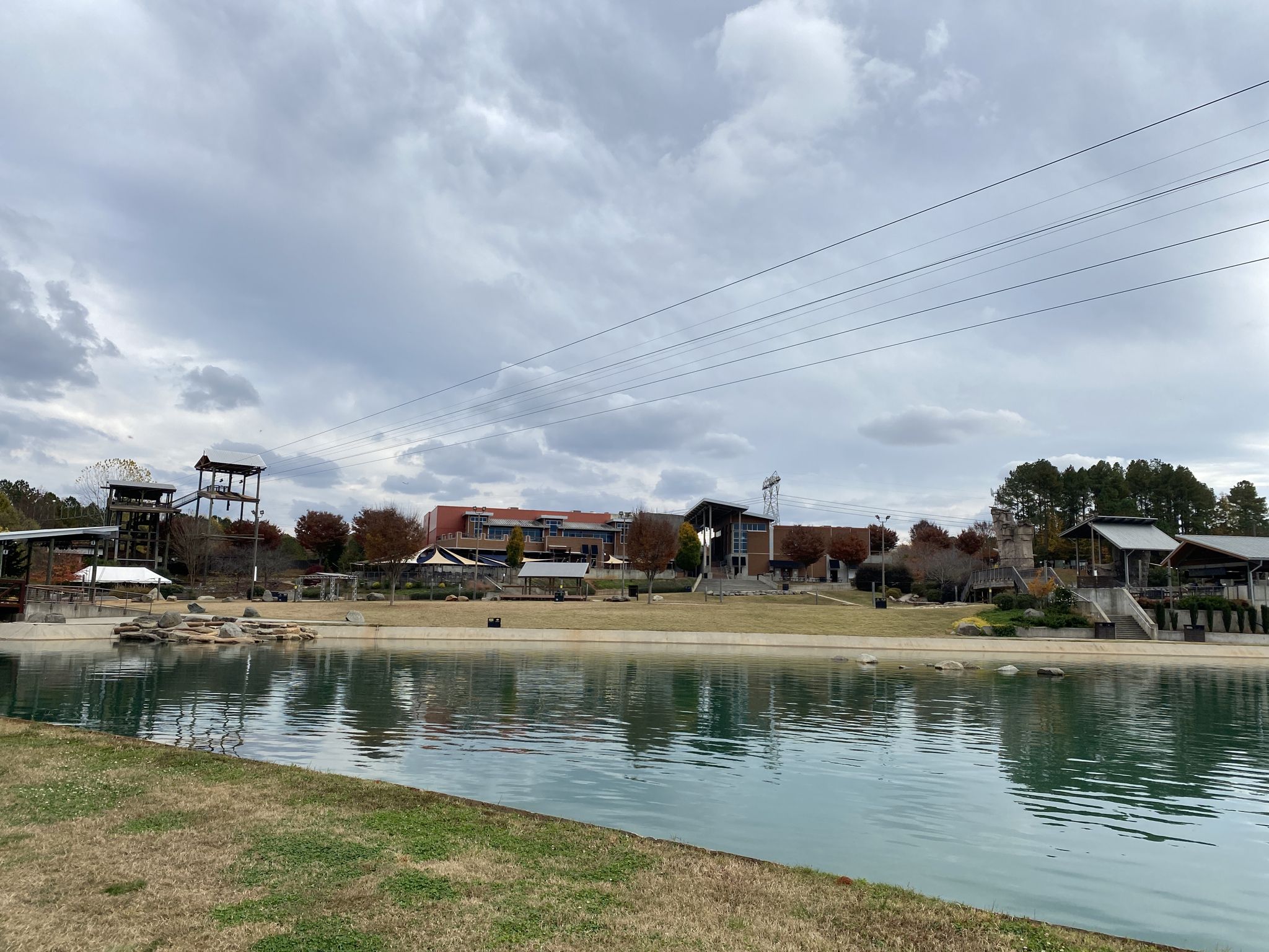 Overcast view of a lake with buildings, structures, and zip lines overhead. - Running loop from Hawk Island