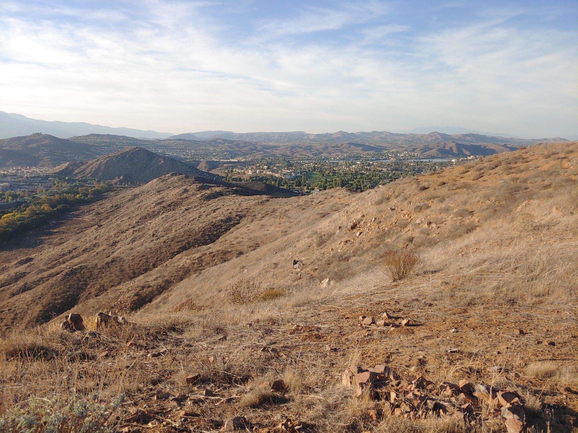Expansive view of dry hillsides overlooking a distant town under clear skies. - Creek to Flag Trail