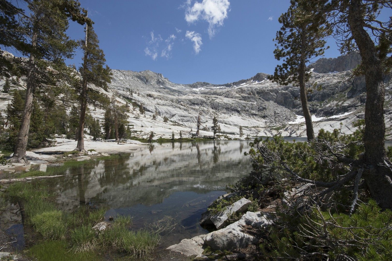 A calm lake reflecting mountains and trees under a blue sky. - Tableland Pass via Lakes, Alta, and Panther Gap Loop