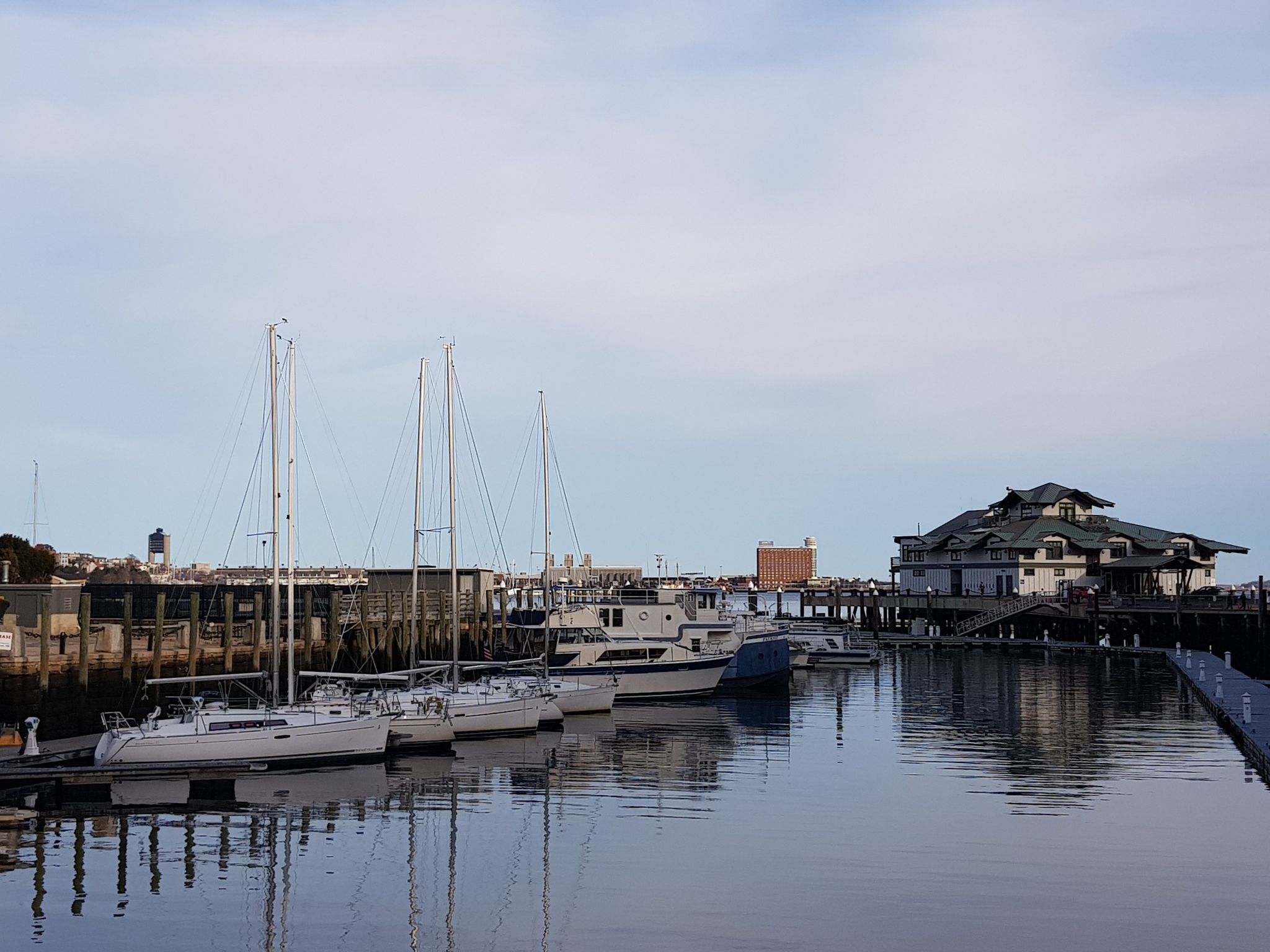 Boats docked in a marina with buildings and a pier under a bright sky. - Massachusetts State House – Boston Common loop from South Station