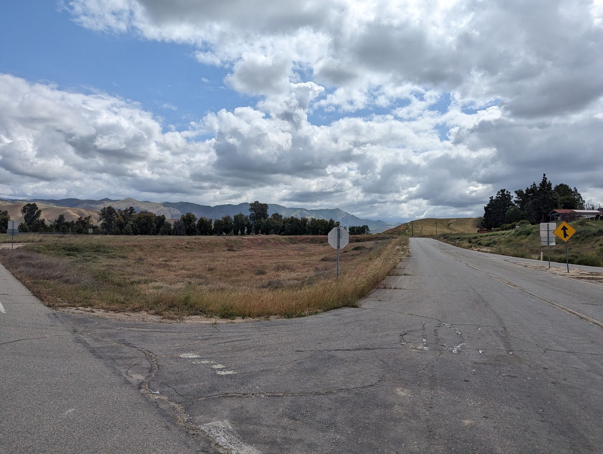 A fork in a paved road next to a dry field under a cloudy sky. - Hart Memorial Park – Hart Park Lake loop from Burger King Parking Lot