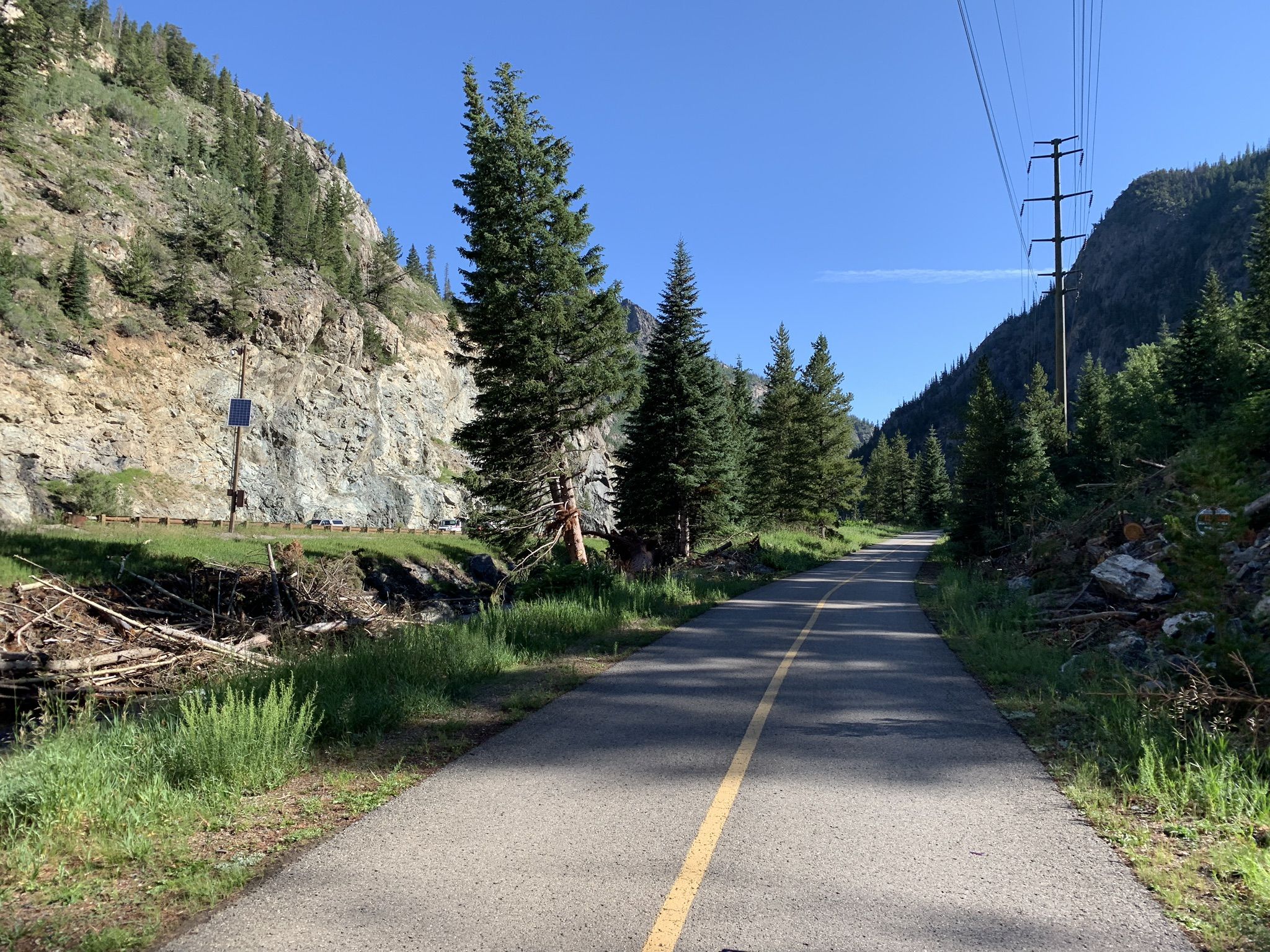 Paved road through a rocky, forested valley with power lines overhead. - Frisco – Copper Mountain loop from Passage Point