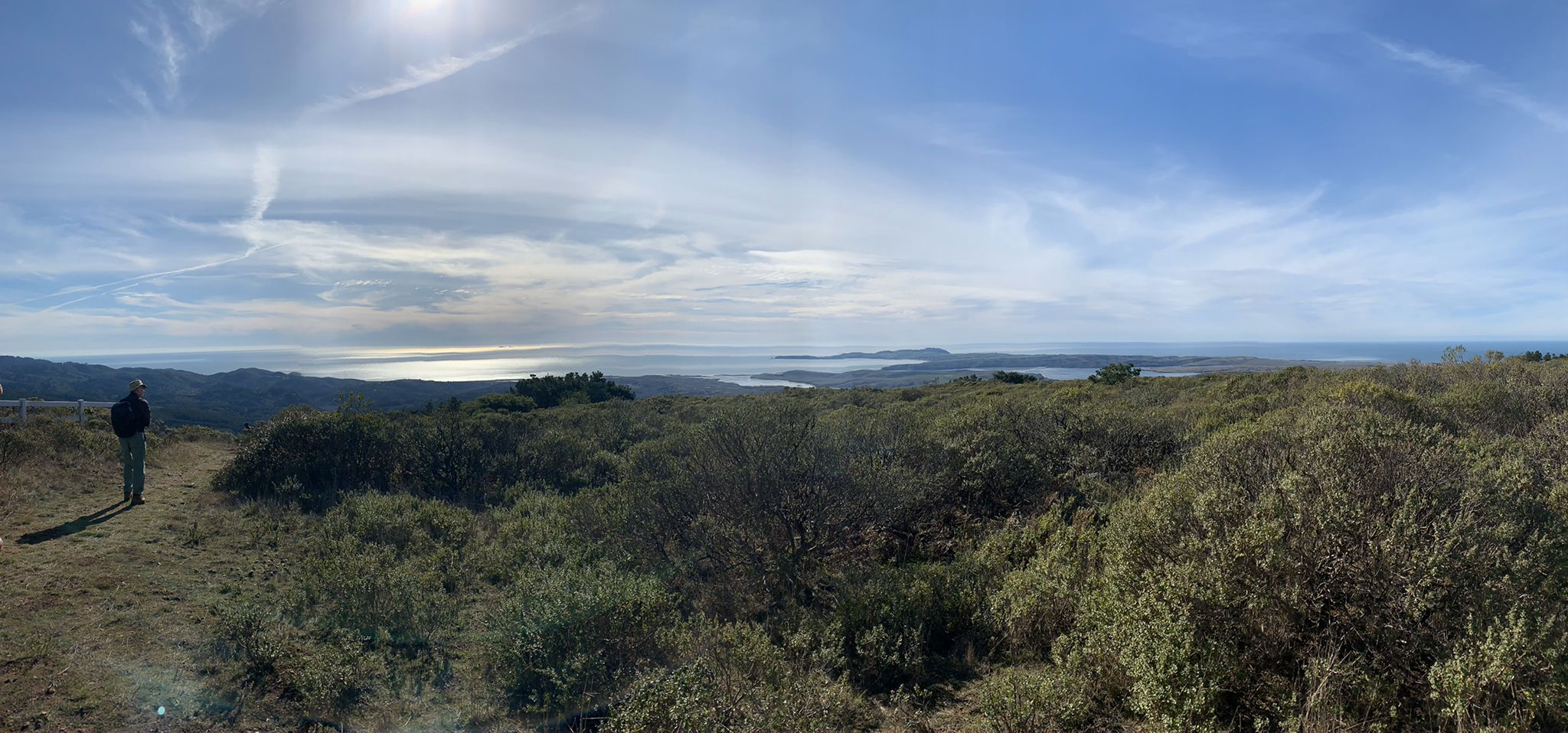 Man on a sunny hill overlooking a vast bay and distant land. - Inverness, Bucklin, Bayview Loop