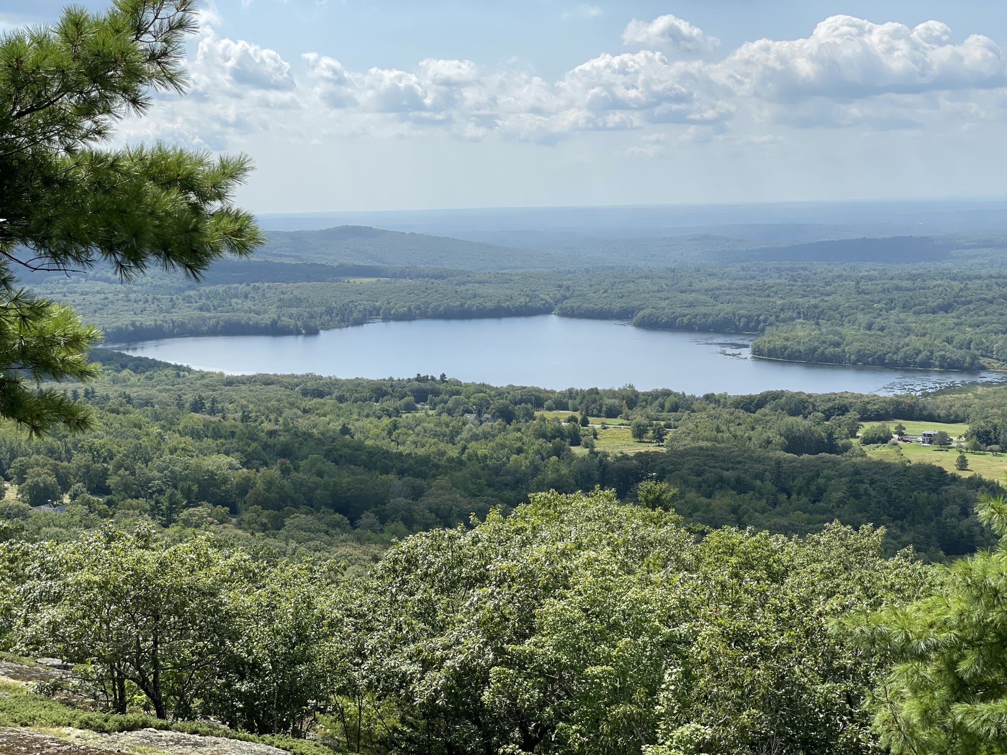 Panoramic view of a large lake surrounded by green forests under a cloudy sky. - Little Ragged and Ragged Mountain Loop