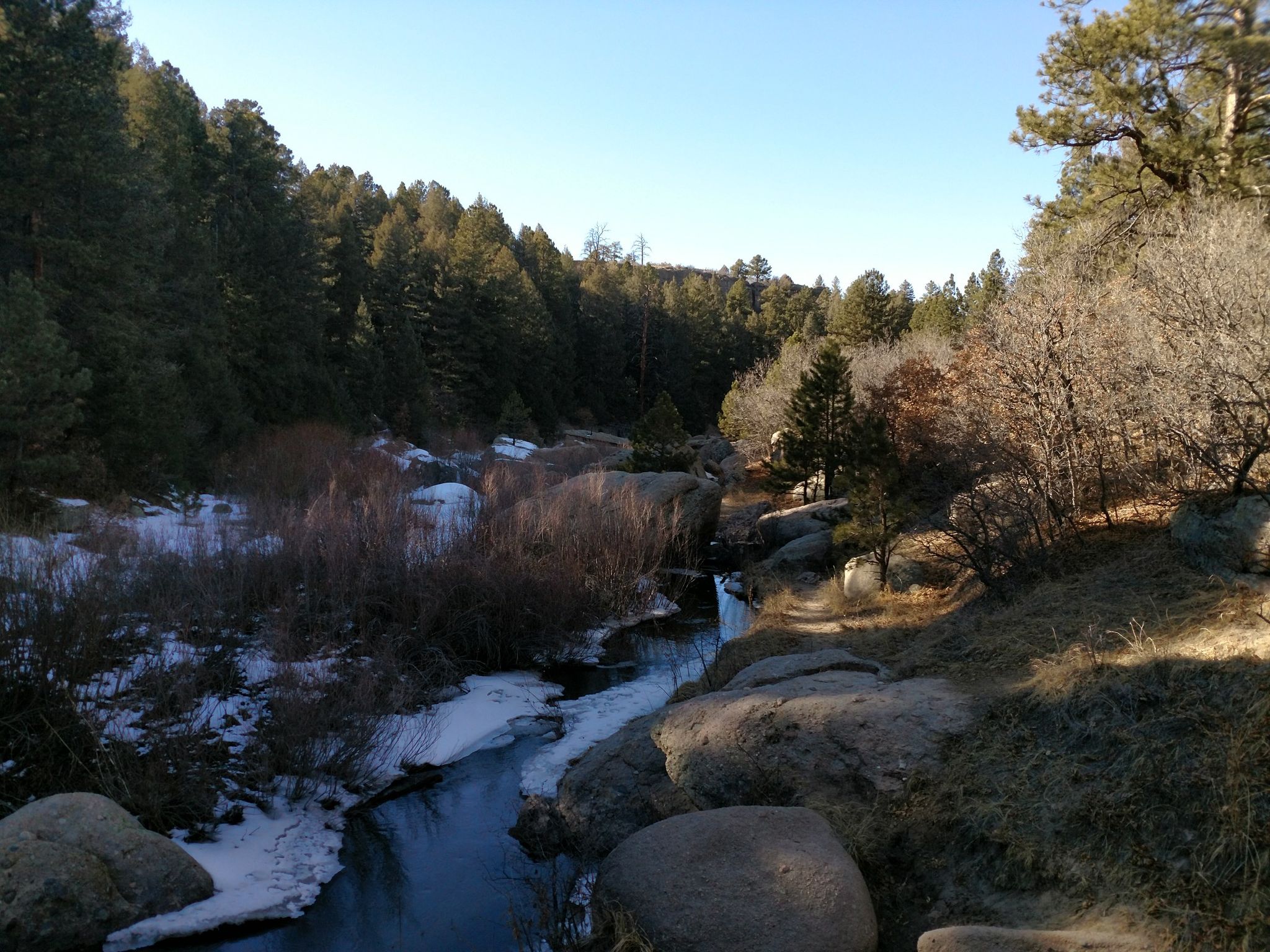 Icy river flowing through a sunny, forested, rocky landscape. - Inner Canyon and Lake Gulch Trail Loop