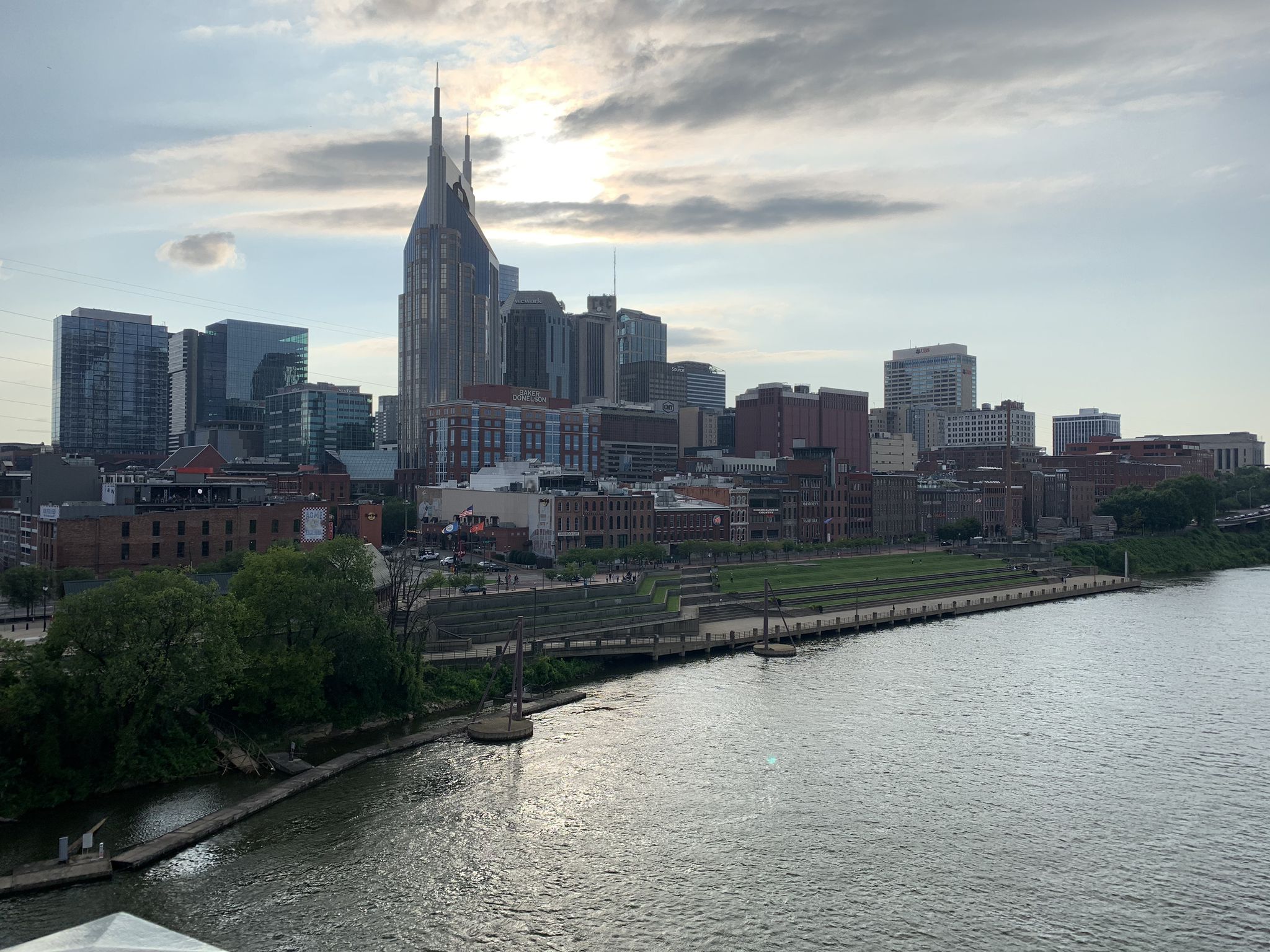 City skyline with a spired building, river, and cloudy sunset sky. - Downtown Nashville and Centennial Park loop via the Cumberland River Greenway