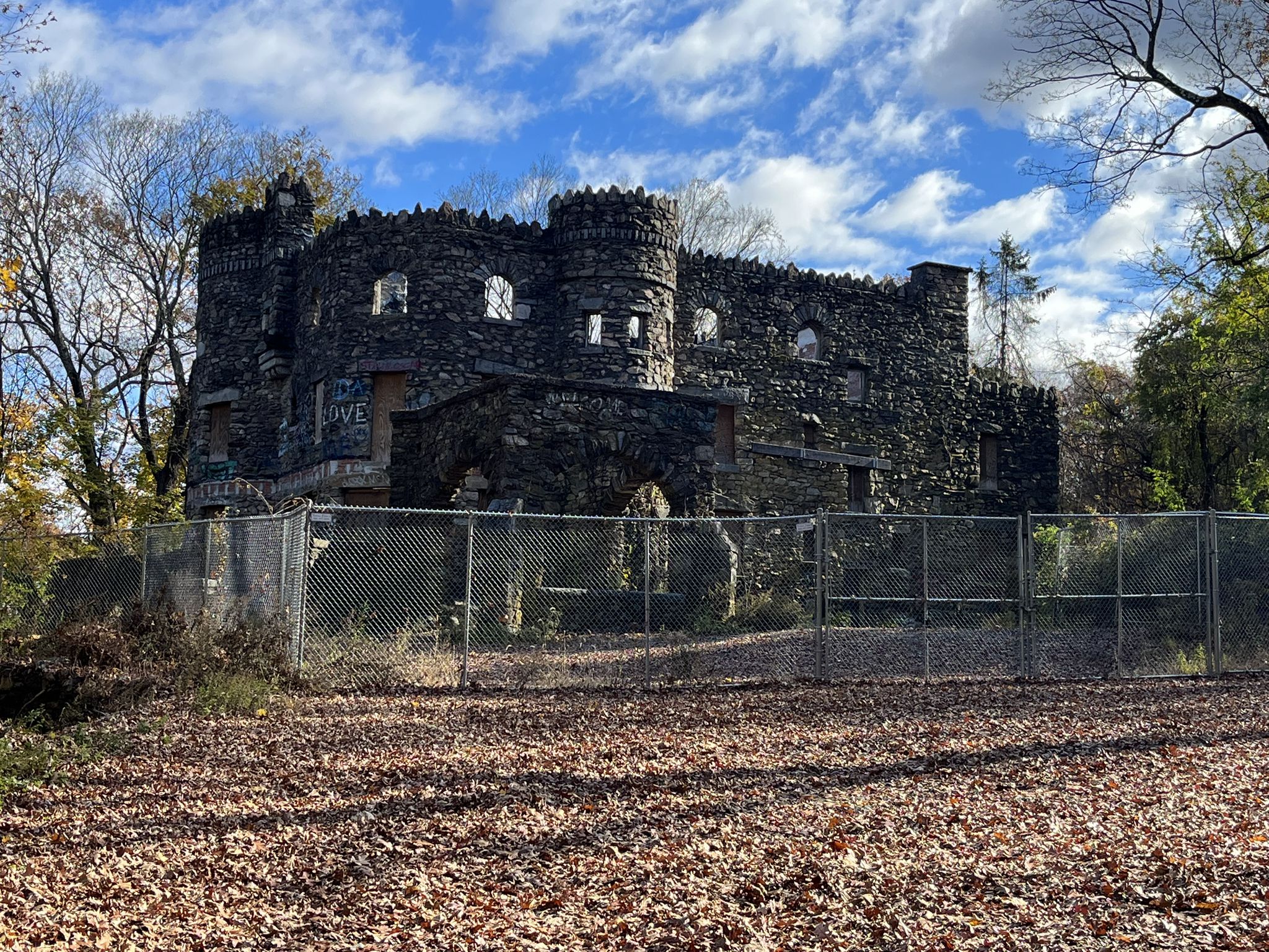 Stone castle-like building with turrets behind a chain-link fence on a sunny day. - Wooden Bridge in Ridgefield – Hearthstone Castle loop from Ridgefield