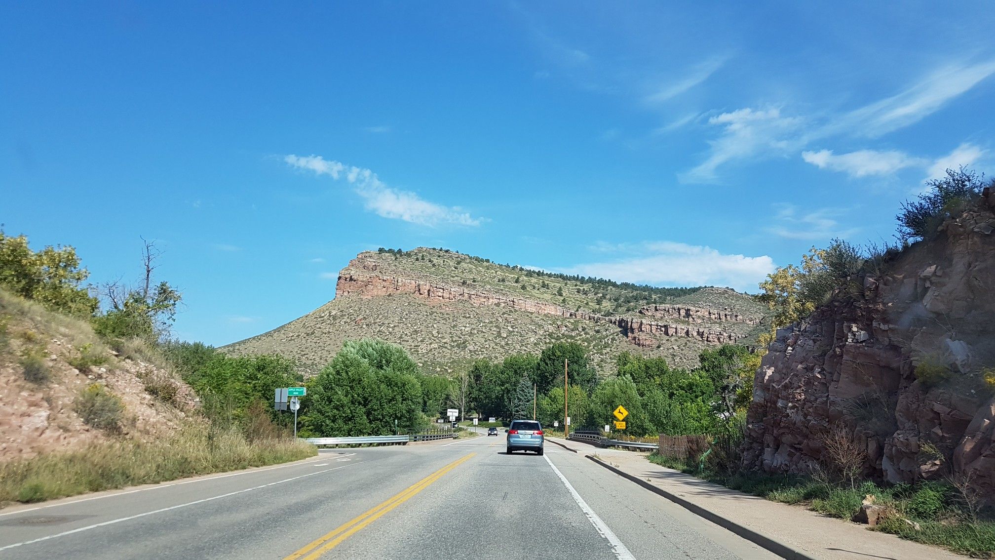 Road leading towards a large, flat-topped mountain under blue sky. - Lower Bitterbrush Trail – Hall Ranch Trailhead loop from Lyons