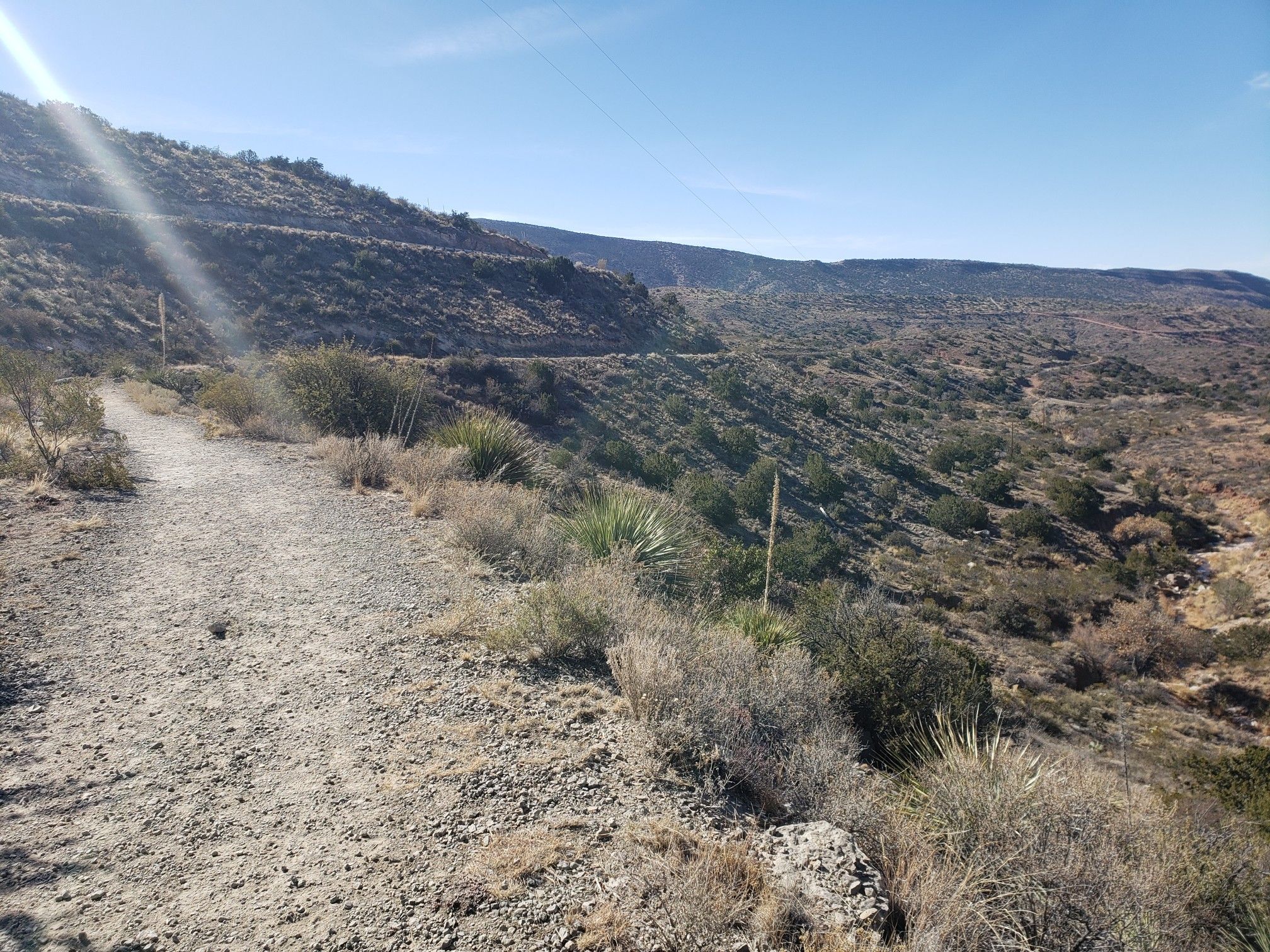 A sunlit dirt path winds through arid, brush-covered hills under a clear sky. - Bridal Veil Falls and Grand View Trail