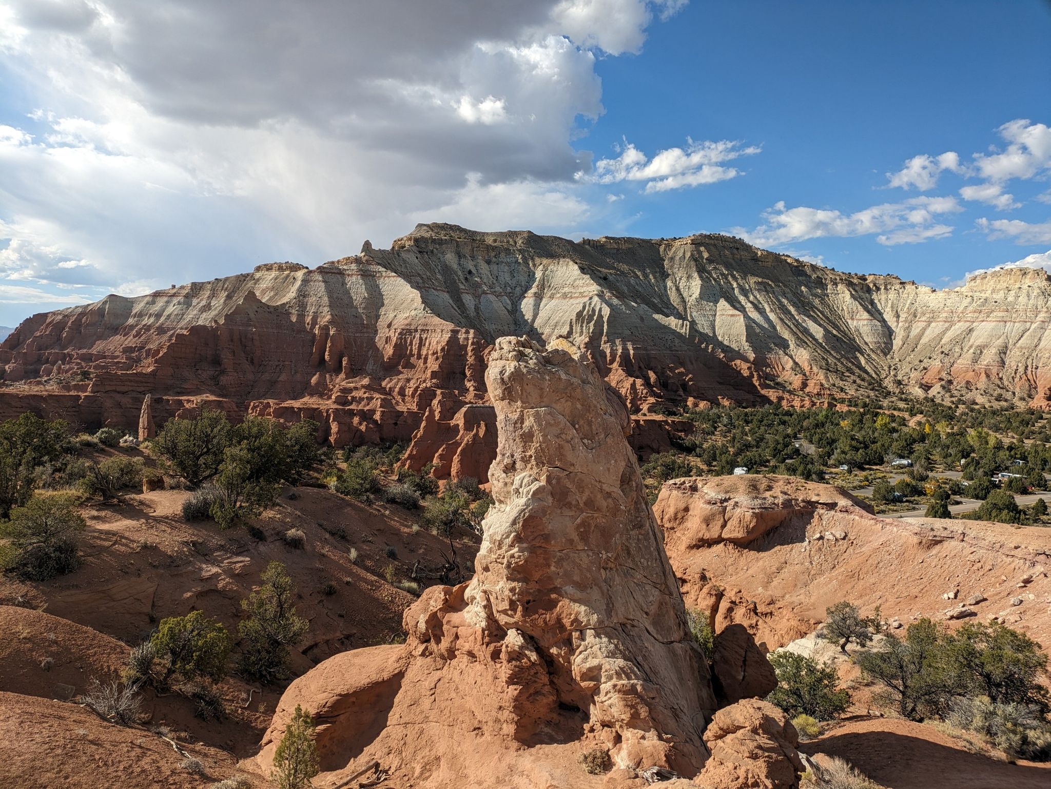 Tall rock spire in foreground, layered mountains in background, sunny day. - View of Oasis Group Campground – Angel's Palace Overlook loop from Kodachrome Basin State Park