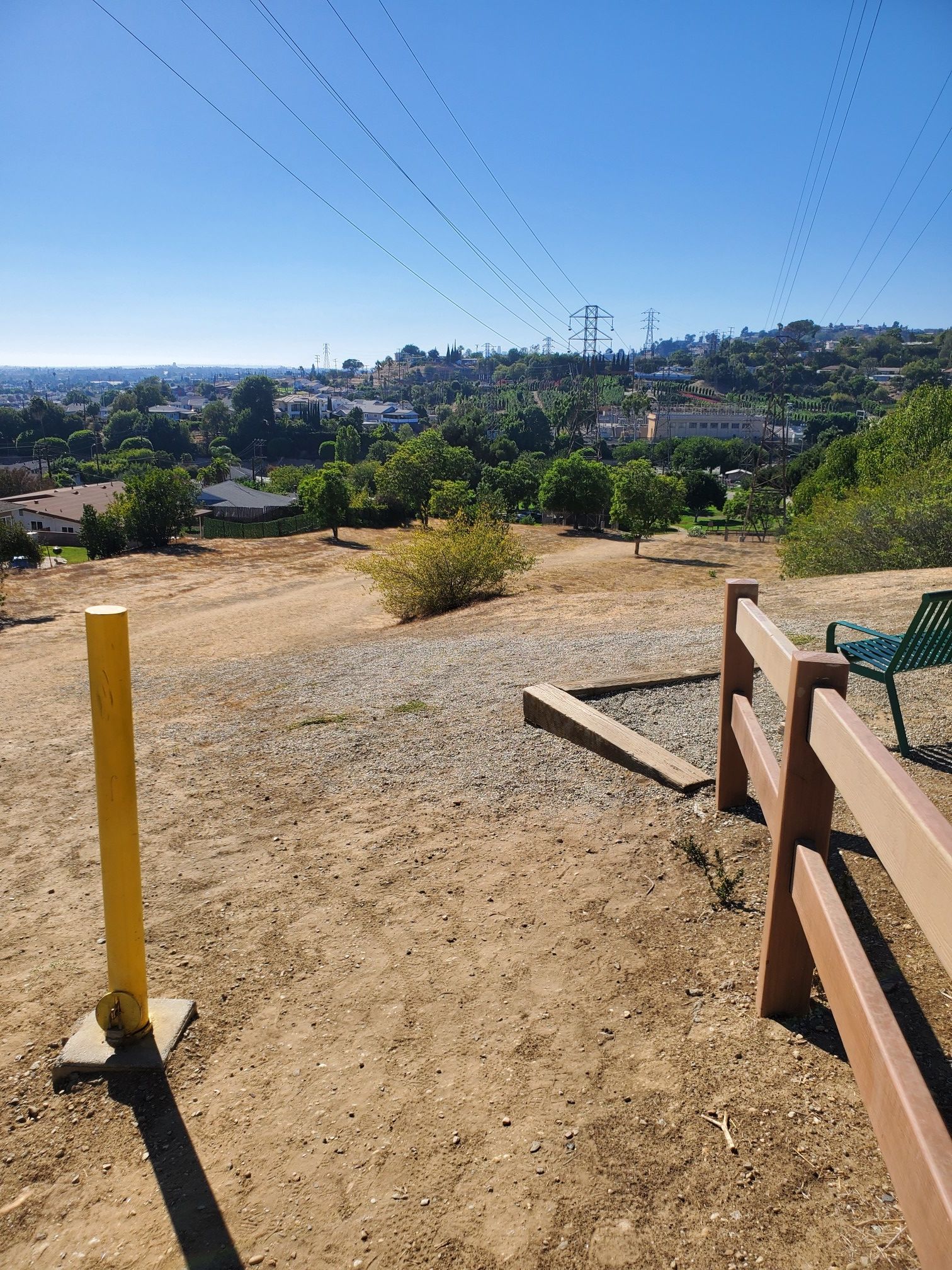 Sunny view of a dry, hilly landscape with a dirt path and distant town. - Edison Trail