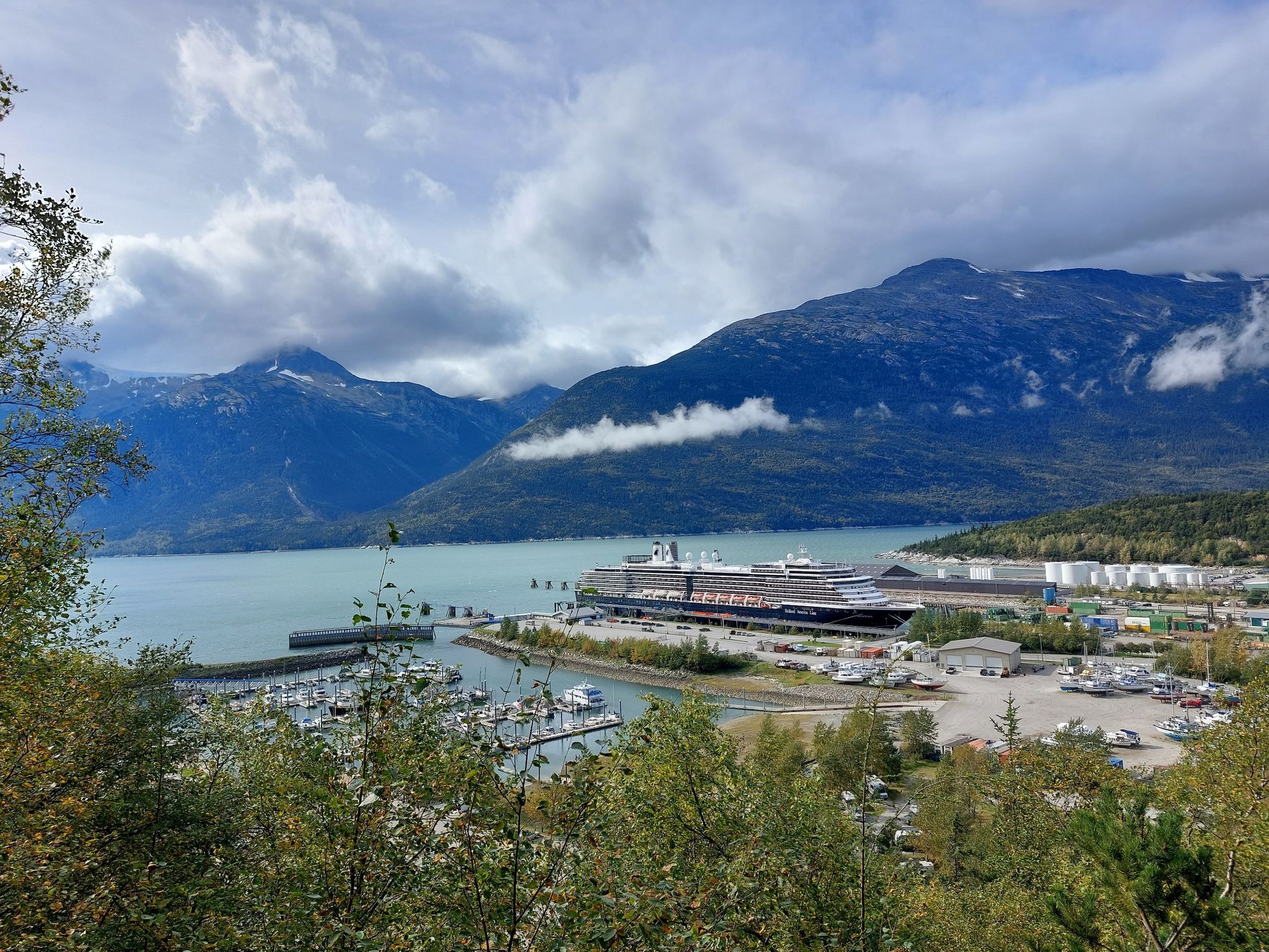 Panoramic view of a harbor with a large cruise ship, mountains, and cloudy sky. - Lower Dewey Lake Loop