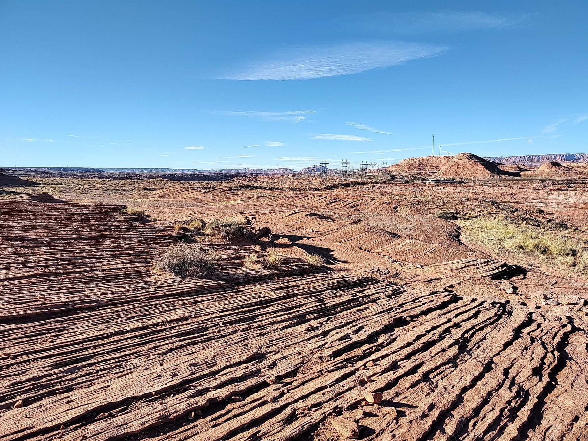 Layered red rock formations and sparse desert vegetation under a clear blue sky. - Hanging Gardens Trail