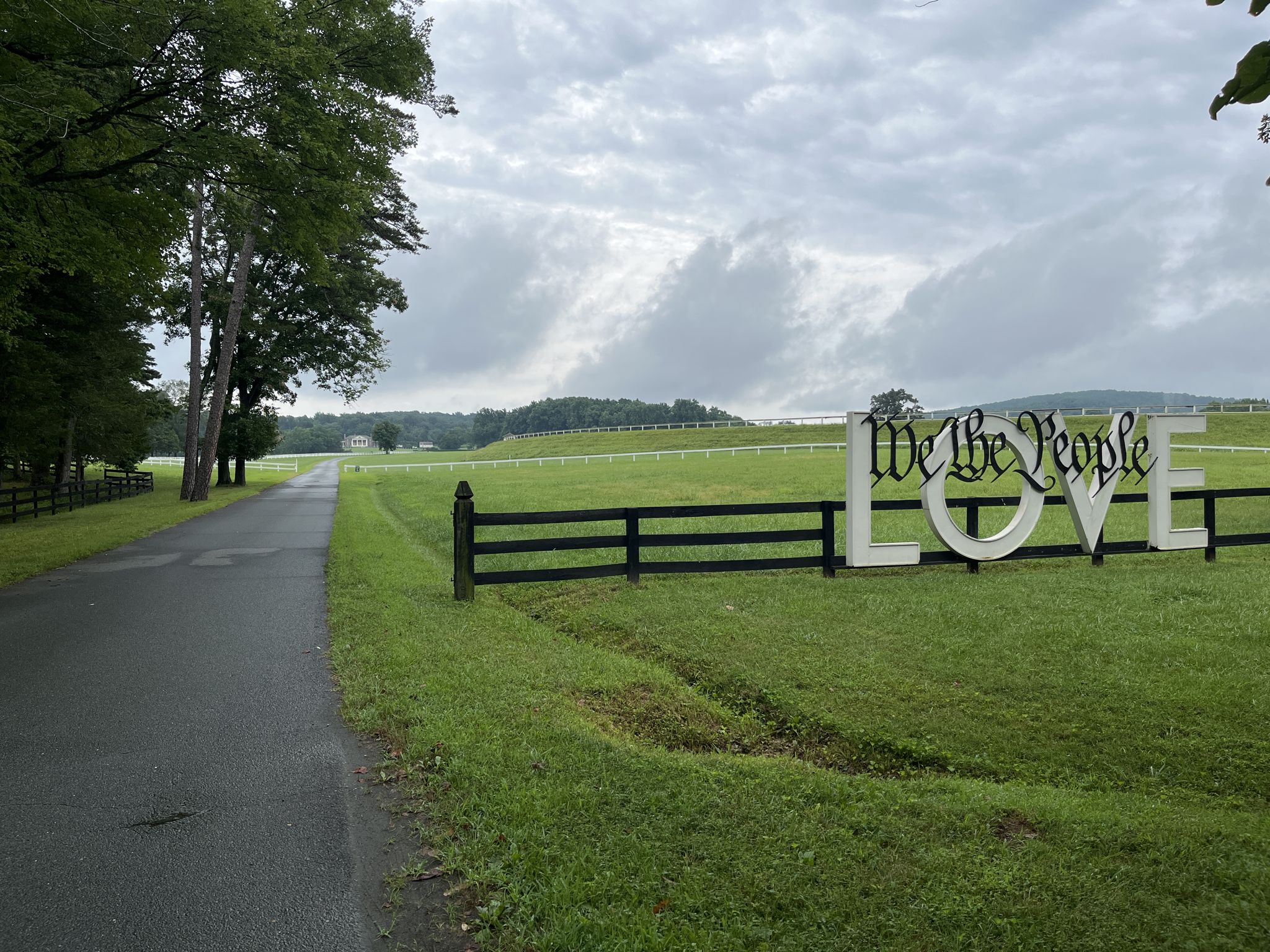 Large 'We the People LOVE' sign in a green field under an overcast sky. - Montpelier Loop Trail