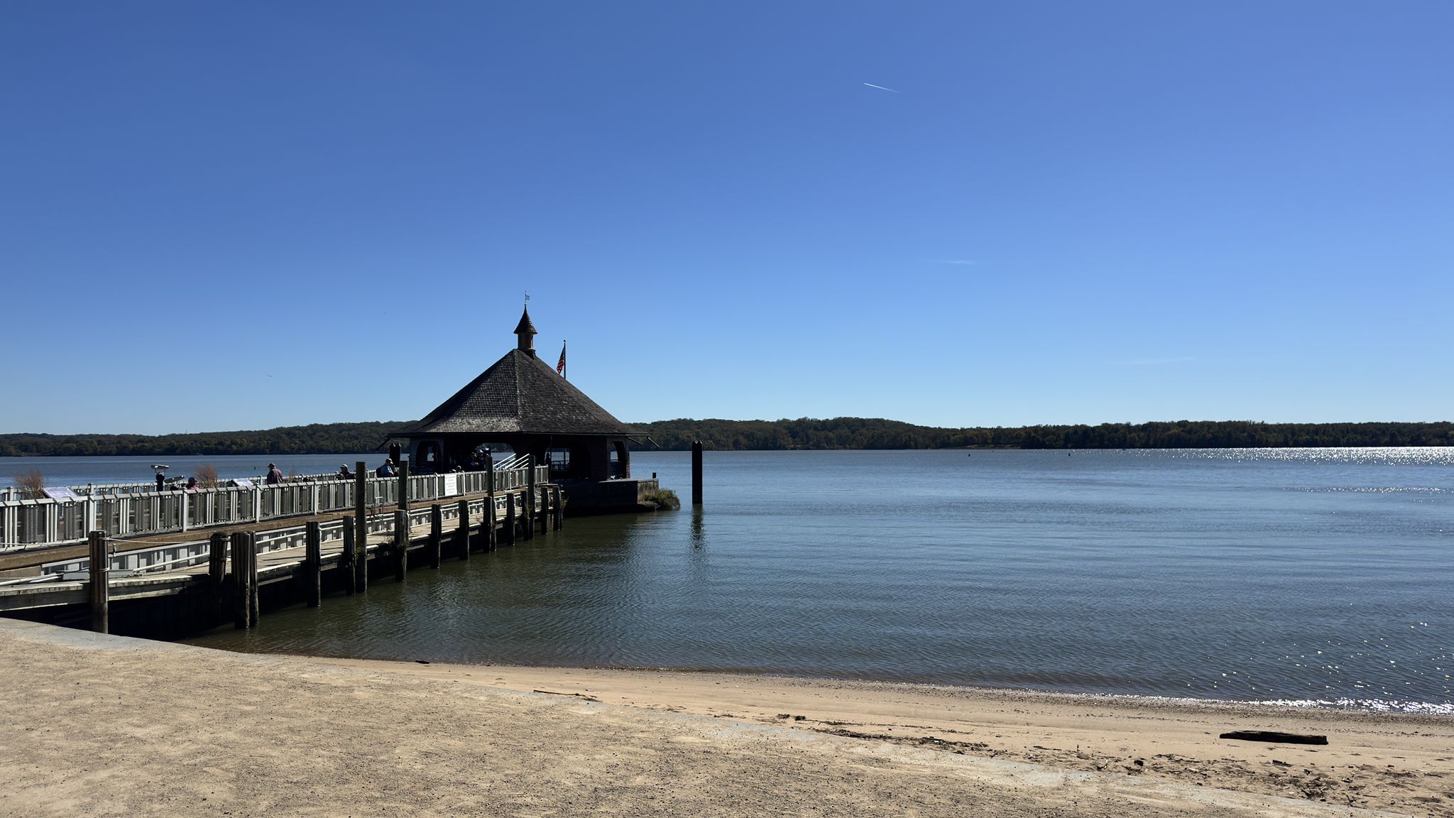 Sunny day at a sandy beach with a pier and covered boathouse over water. - Mount Vernon Loop