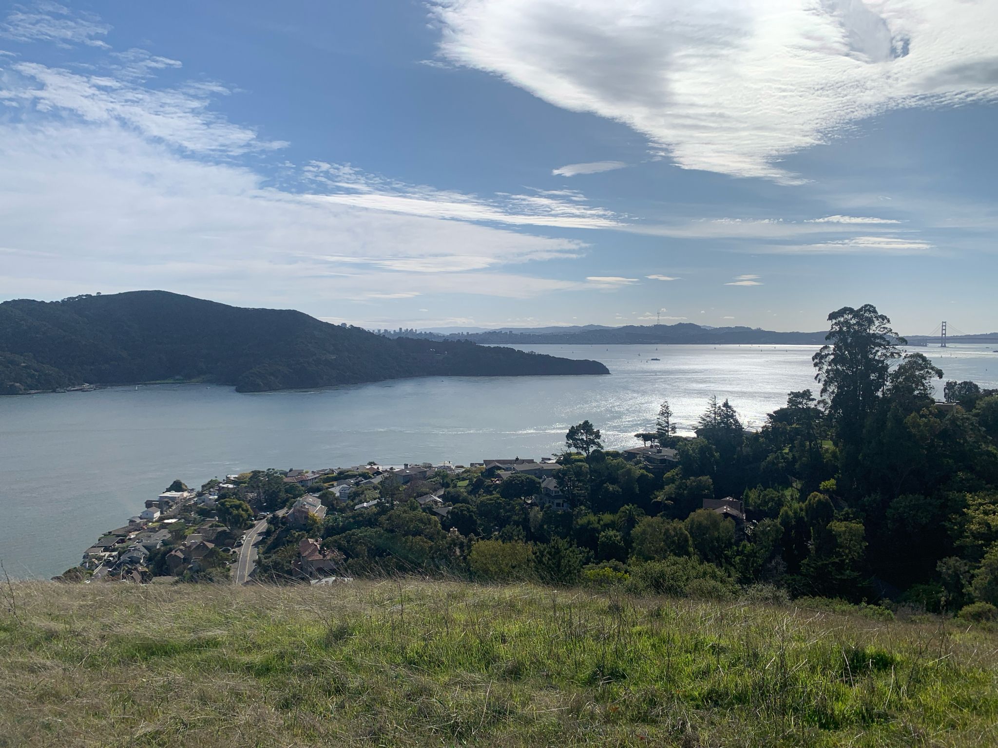 Wide view of a bay, distant hills, and houses under a cloudy sky. - Spanish Loop