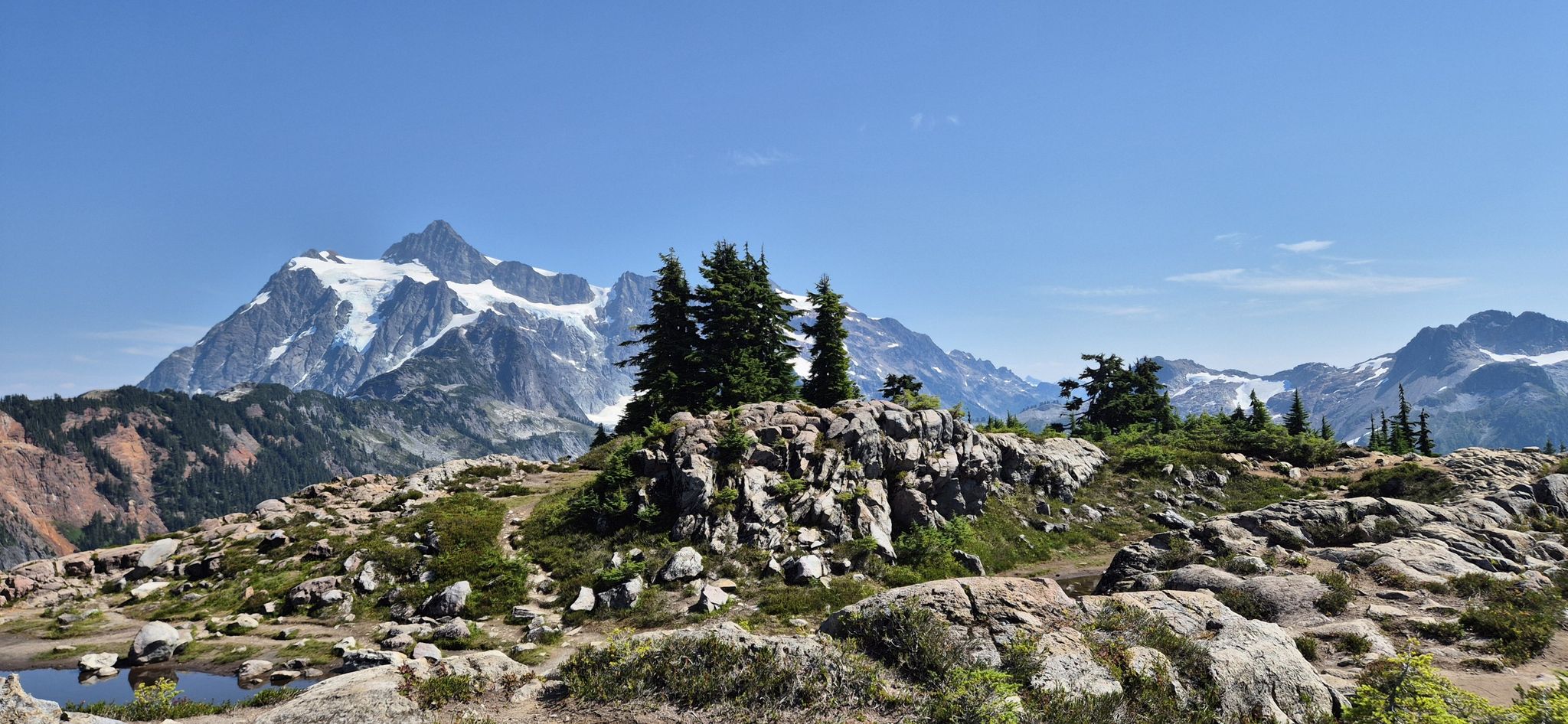 Rocky, treed ridge with a majestic snow-capped mountain in the background. - Mount Baker Highway to Artist Point