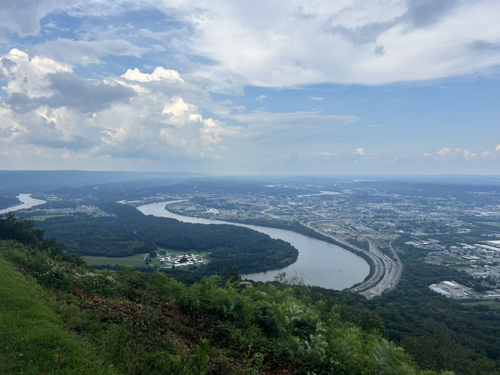 Aerial view of a winding river, city, and green landscape under cloudy sky. - Guild and Lookout Mountain Trails Loop
