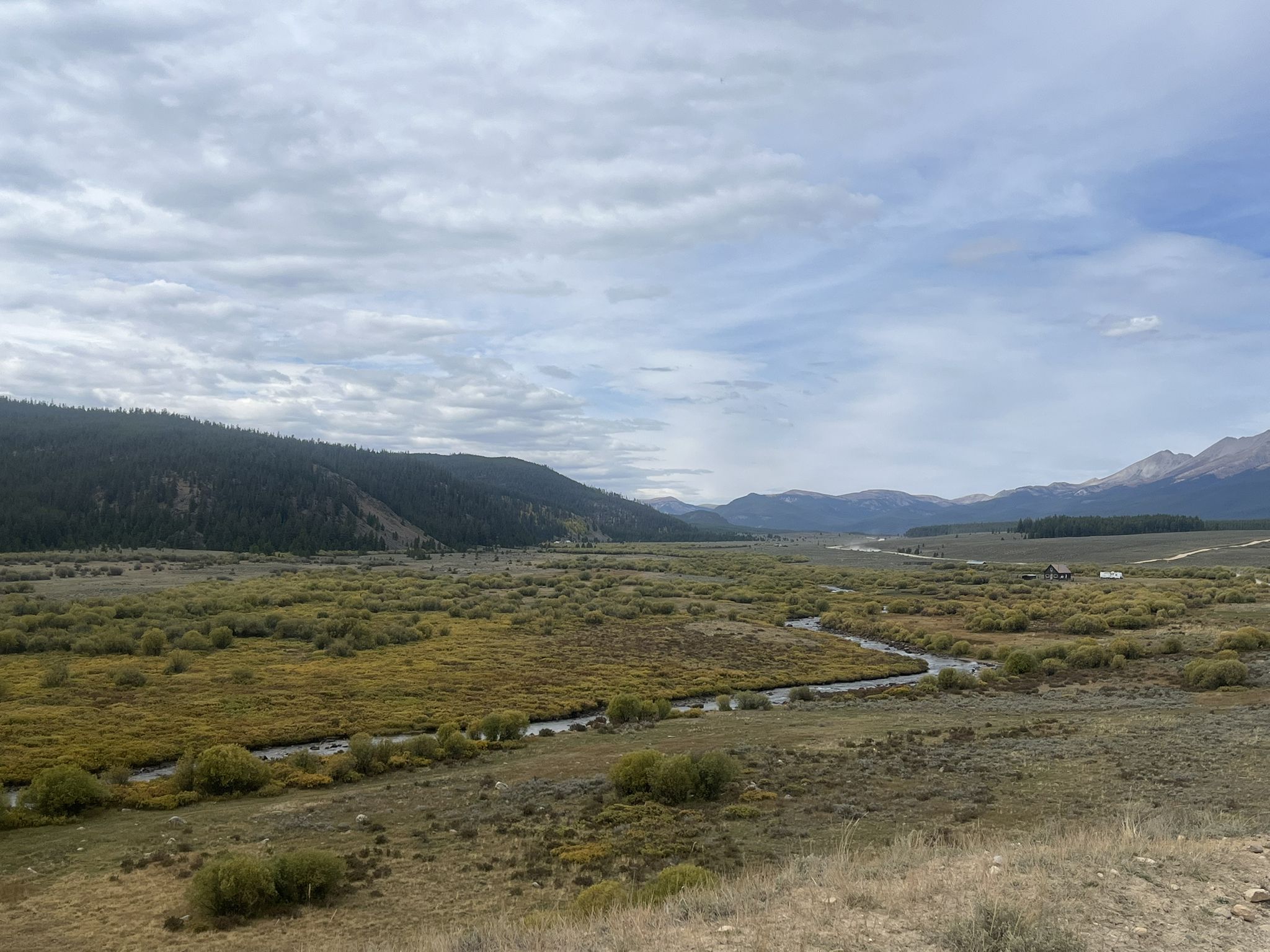 A wide, marshy valley with a winding river under an overcast sky. - Taylor Park Reservoir via Taylor Park River Road gravel