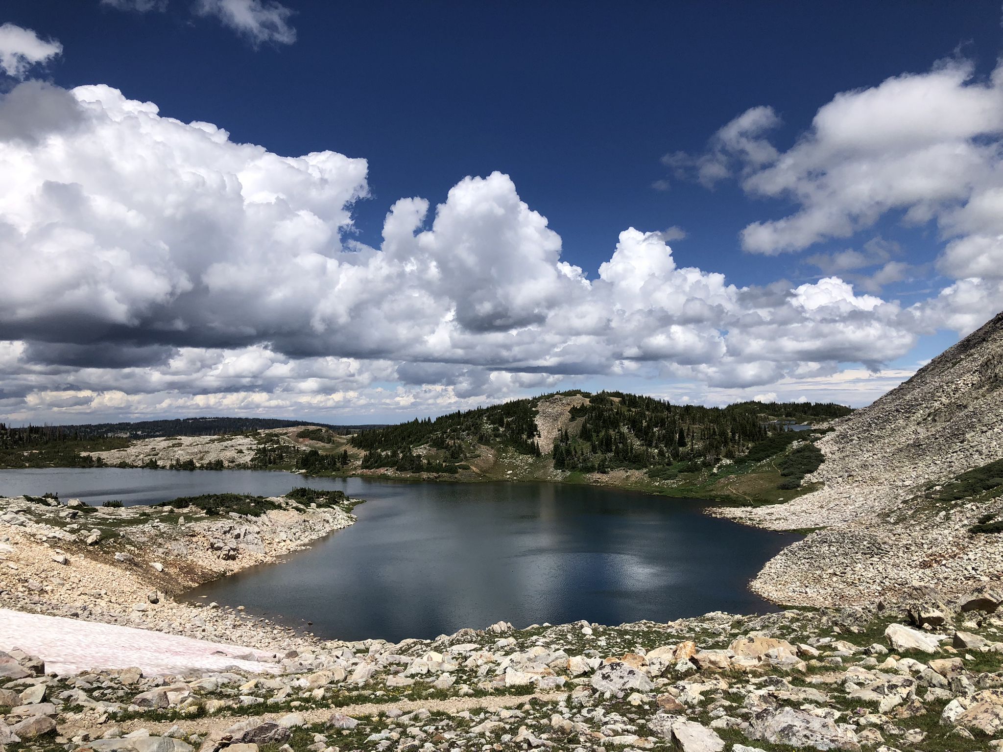 Deep blue lake with rocky shores under a dramatic cloudy sky. - Gap Lakes Trail