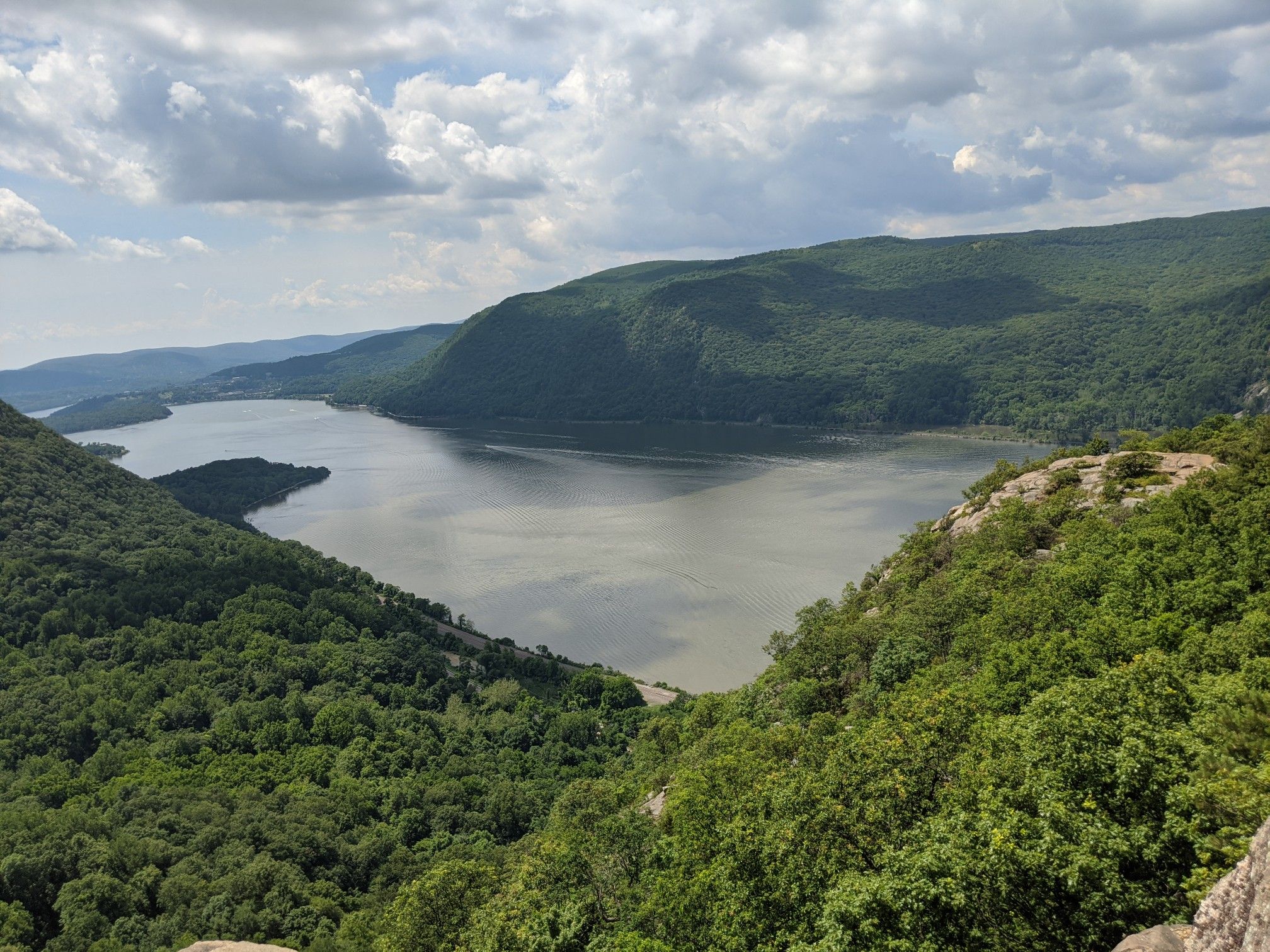 Expansive view of a wide river winding through dense green forests and mountains. - Breakneck Ridge Loop Trail