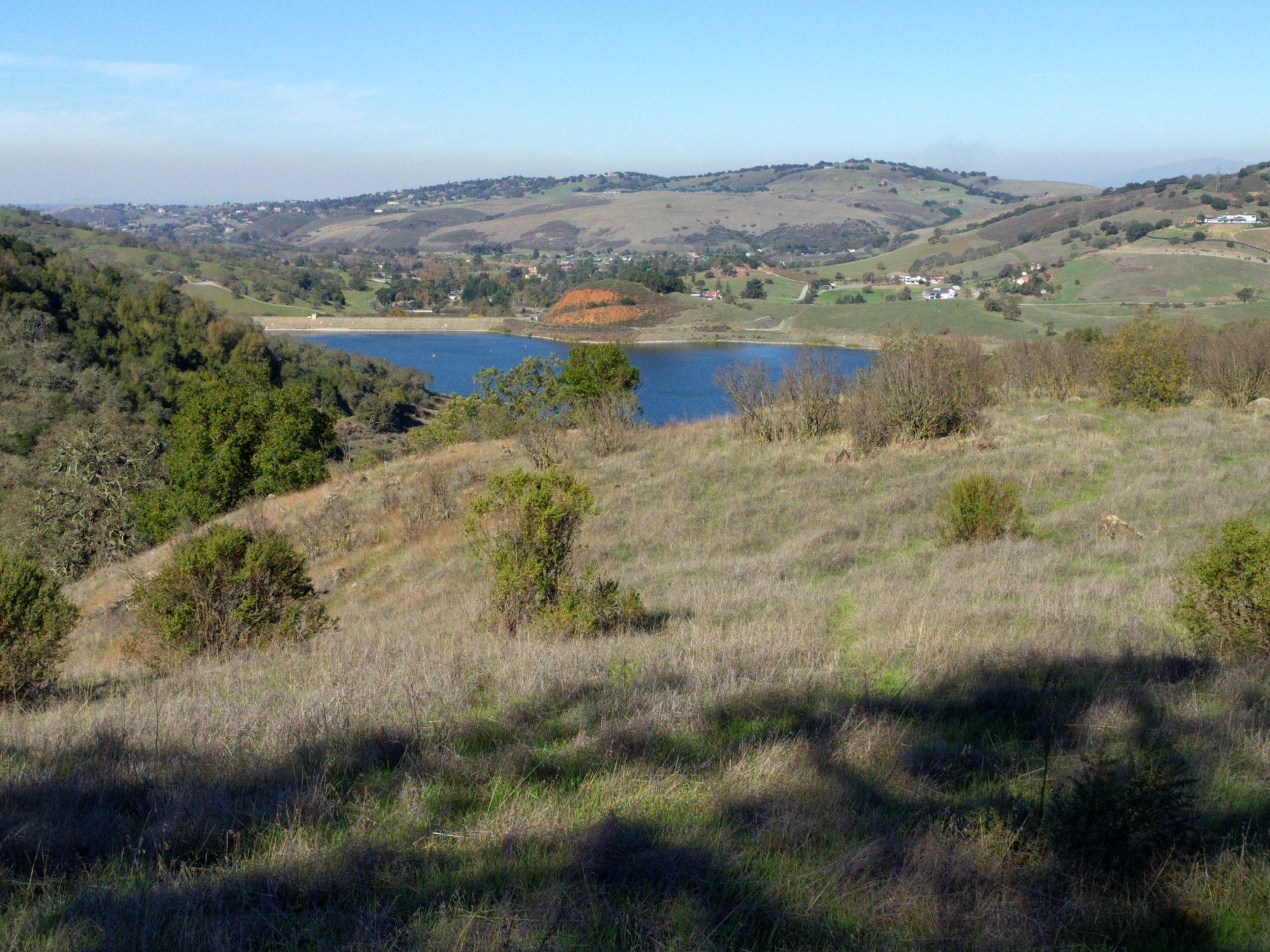 Blue lake nestled among dry, rolling hills under a clear sky. - Calero County Park – Los Cerritos Pond loop from Holthouse Ranch Reserve