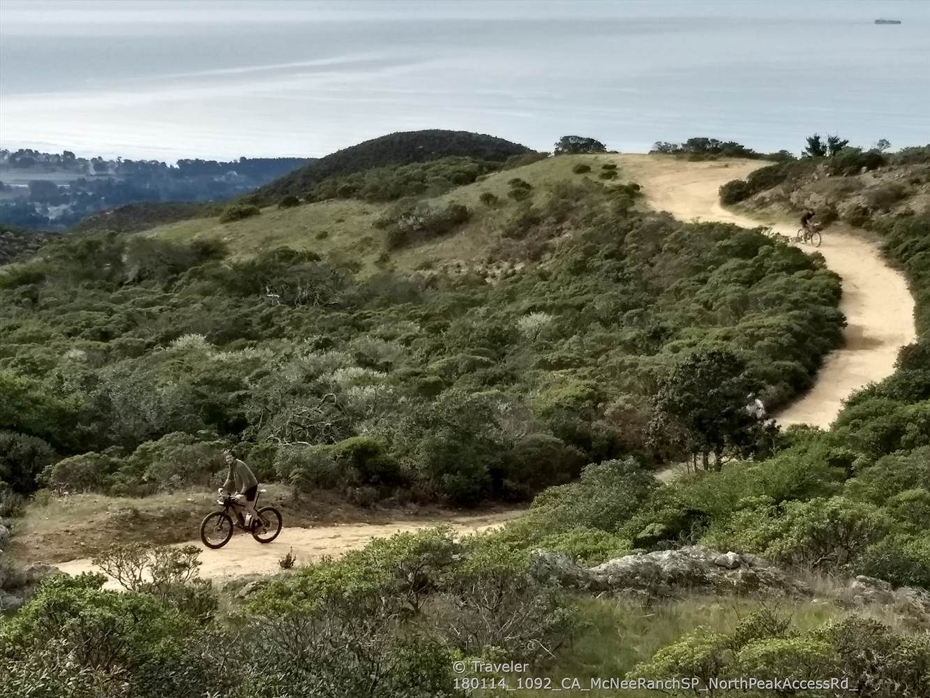 Mountain biker on a winding dirt trail with ocean in the distance. - Montara Mountain and North Peak Loop