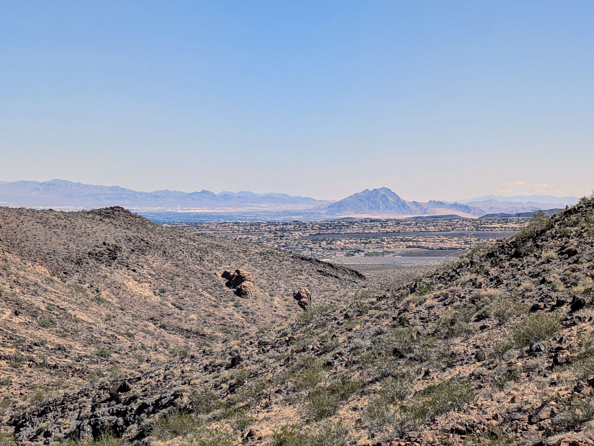 Expansive desert valley with distant mountains under a clear blue sky. - Petroglyph Trail and Cowboy Trail Loop