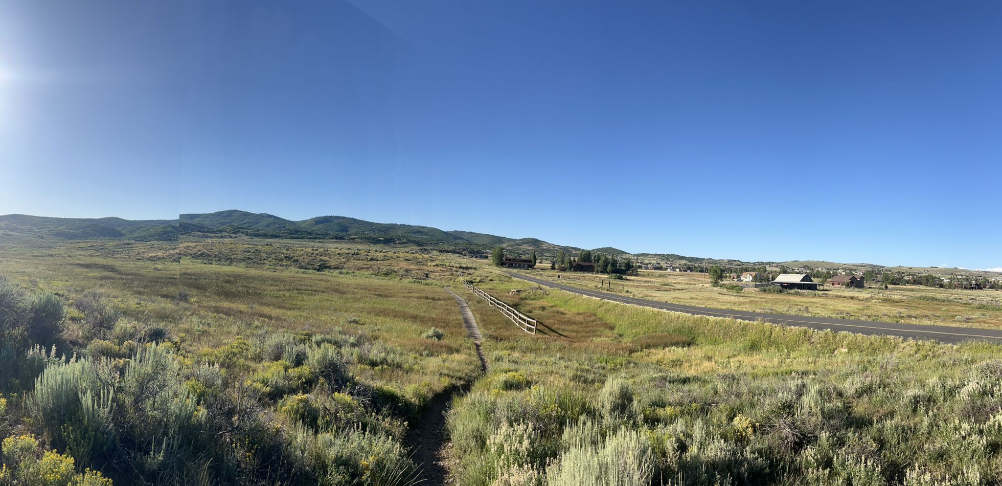 Panoramic view of a sunny, expansive grassy field with distant mountains. - Beaver Pond – Stealth Trail loop from Awards bus stop