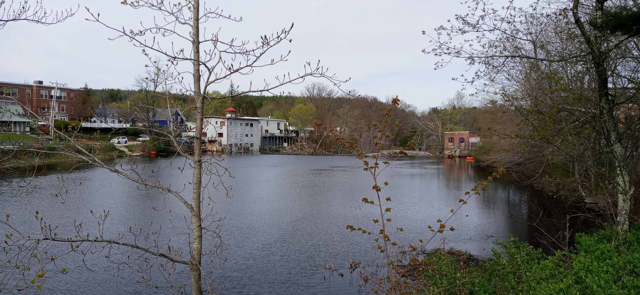 Calm lake surrounded by buildings and bare trees under an overcast sky. - Shirley Hill – Goffstown Town center loop from Goffstown