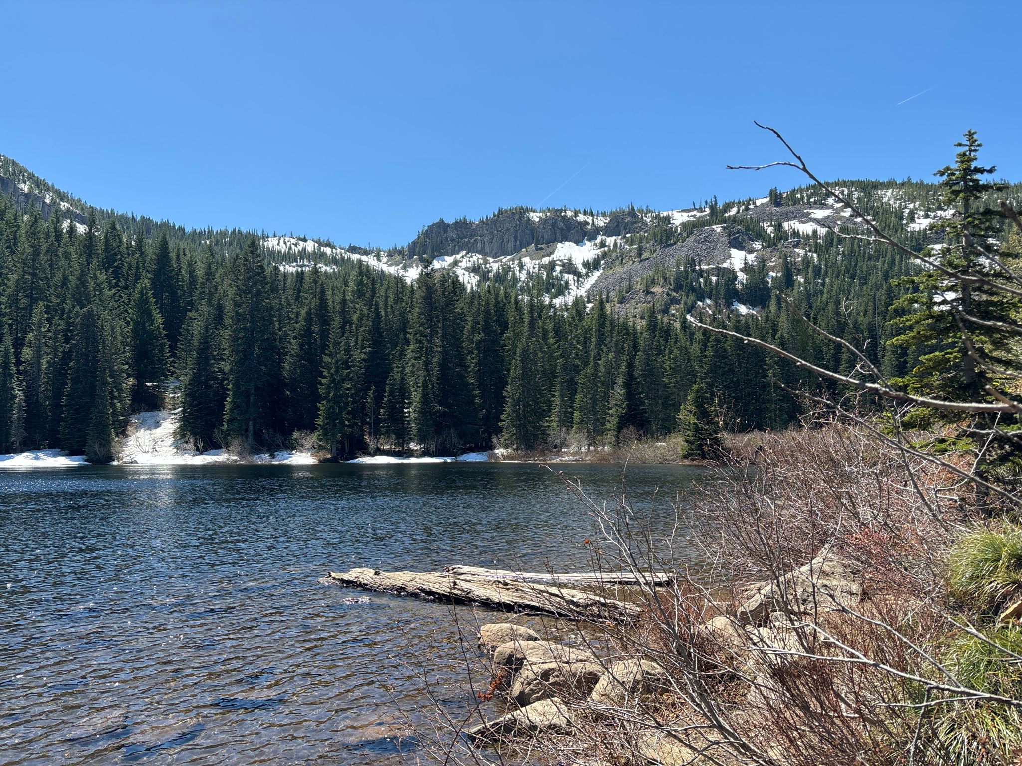 Clear lake with snow-dusted mountains and dense forest under a bright blue sky. - Mirror Lake Trail #664