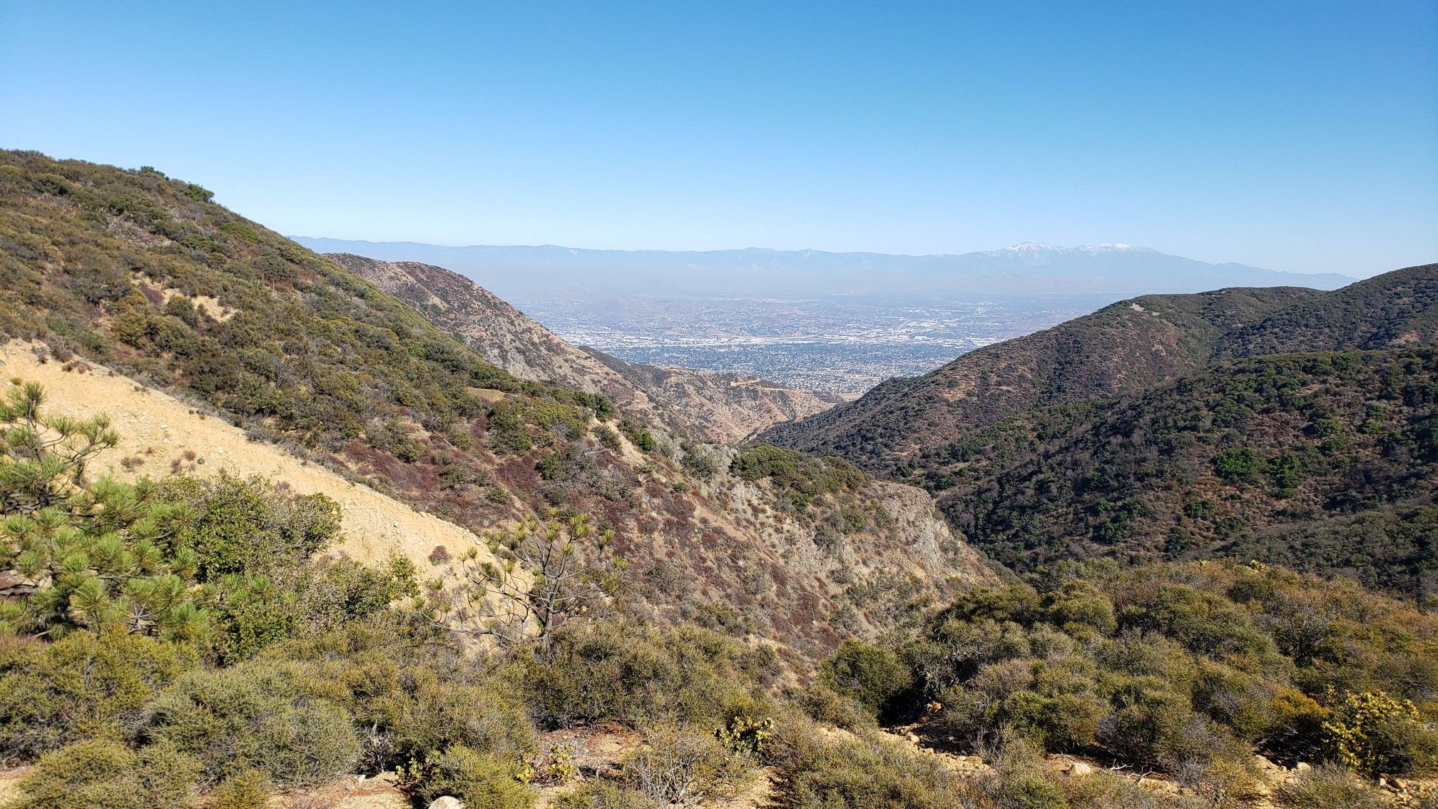 A deep valley with brush-covered hillsides and a hazy distant city. - Beeks Place – KSOX Doppler Radar Tower loop from Oak Street Creek Reservoir