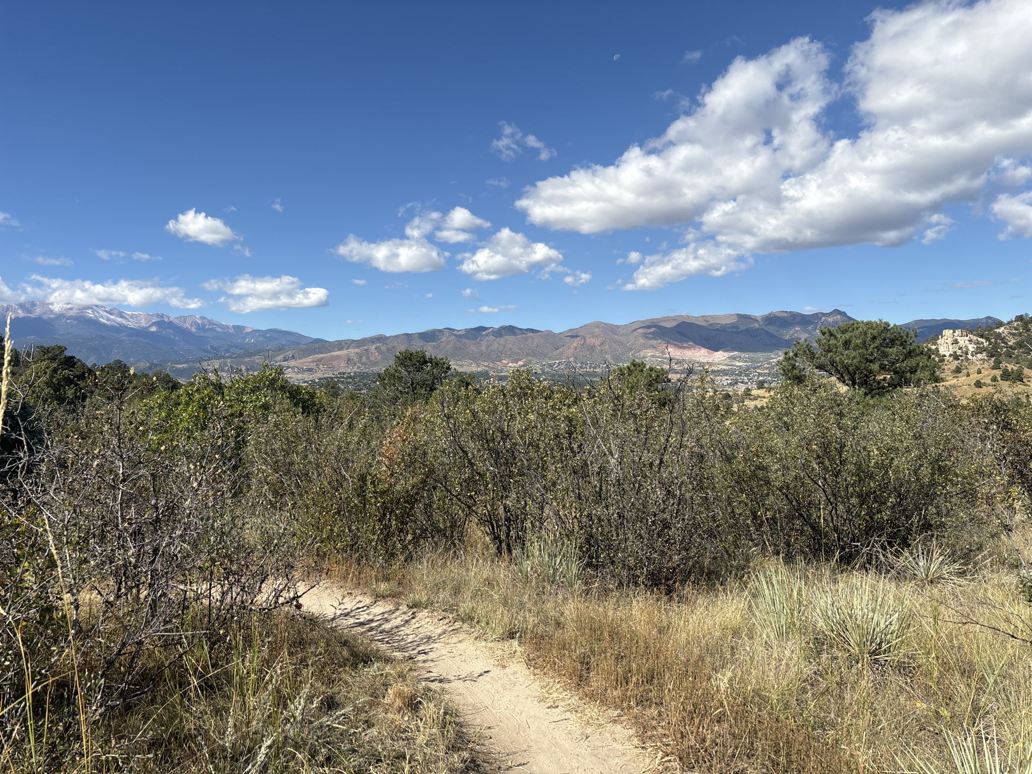 Dirt path through dry brush, mountains in distance under blue sky. - Pulpit Rock – Austin Bluffs Trail loop from University of Colorado Colorado Springs