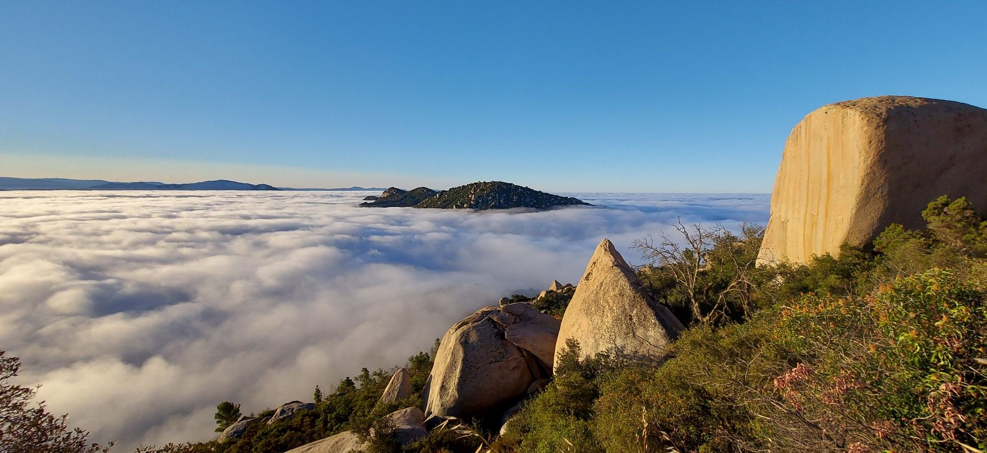 Panoramic view of a cloud inversion over mountains, large boulders in foreground. - Potato Chip Rock via Mount Woodson Road