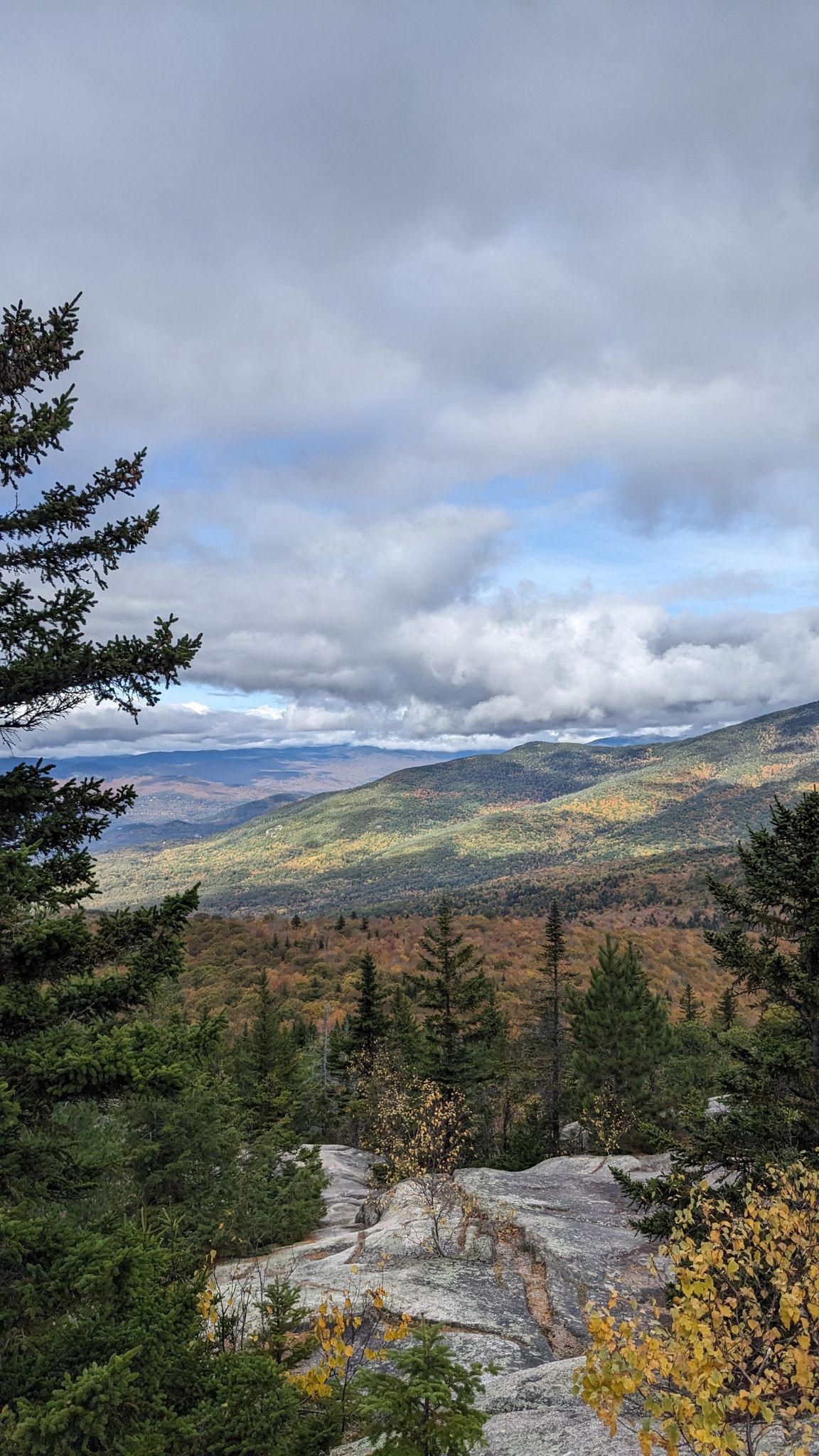 Rocky mountain overlook with autumn trees and sunlit distant peaks. - Black Cap Trail