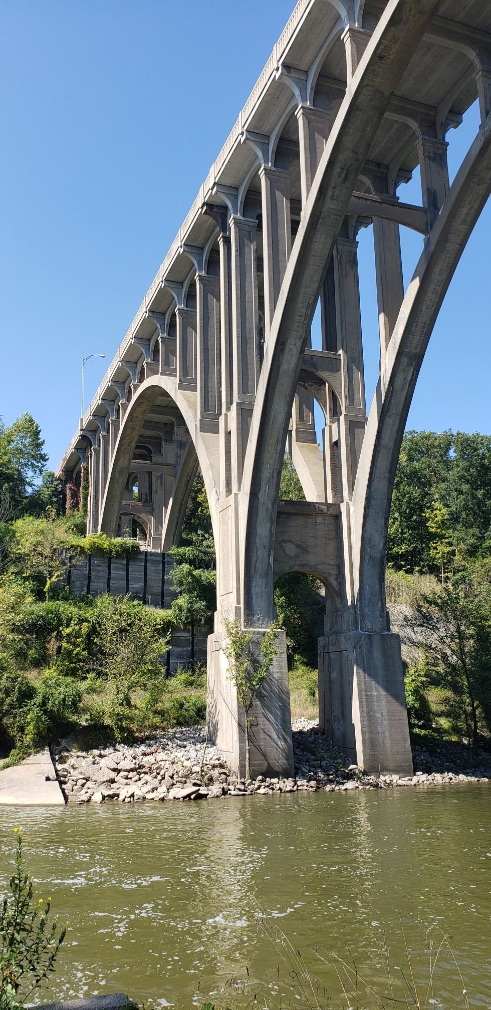 Large concrete arch bridge spans over a river with green trees on a sunny day. - Ohio and Erie Canal Towpath: CanalWay to Rockside