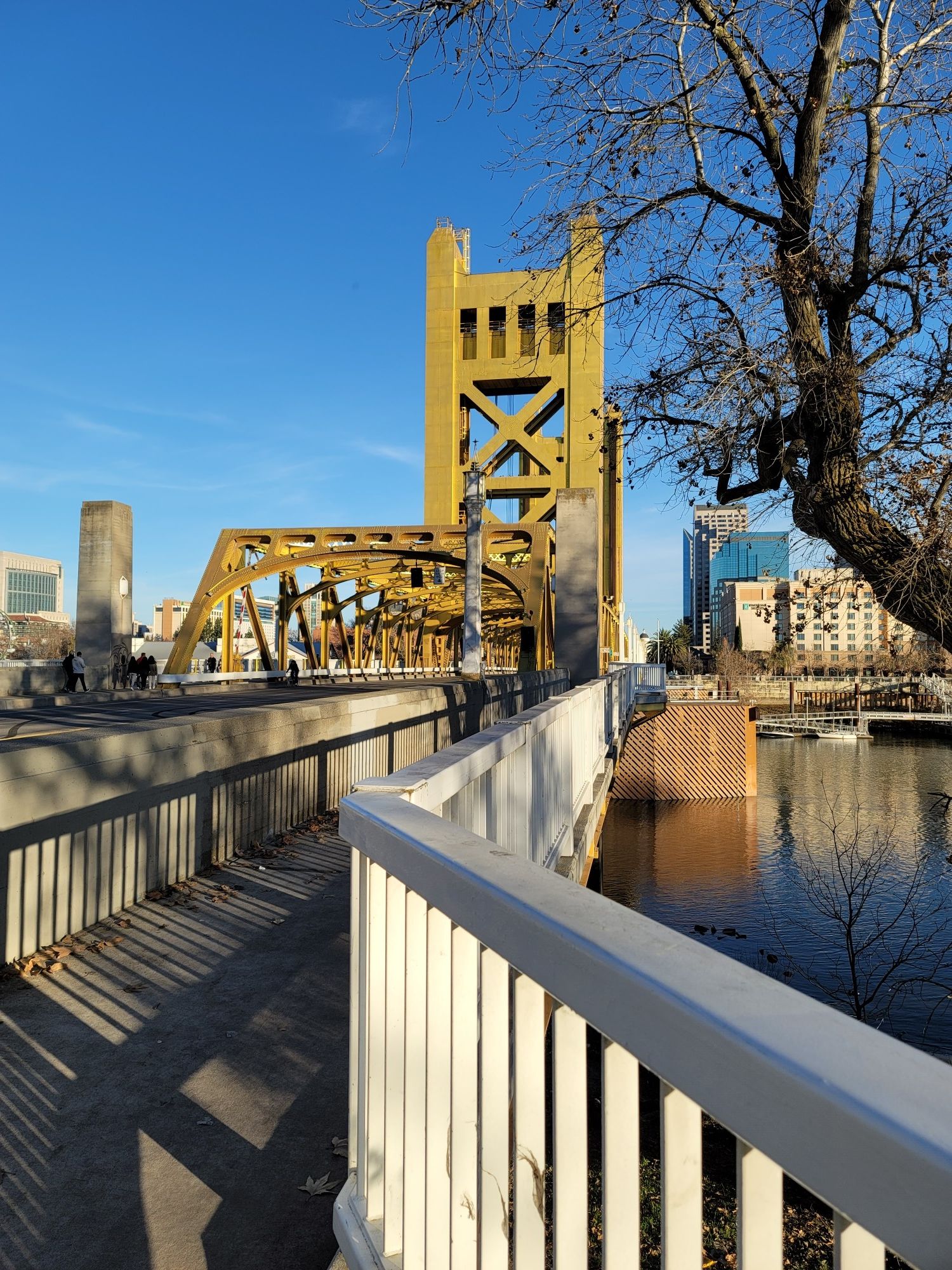Bright yellow bridge over a river on a sunny day, with a white railing. - Tower Bridge loop from Sacramento