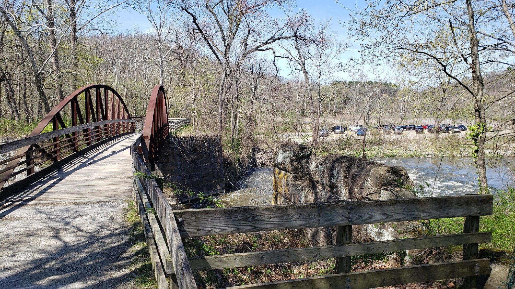 A metal bridge and concrete structure next to a river on a sunny day. - Lock 29 – Cuyahoga River Bridge loop from Akron Northside