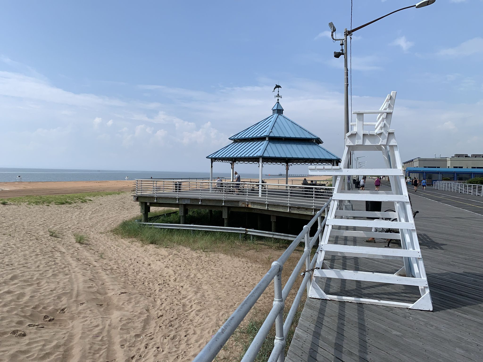 A boardwalk with a blue gazebo and white lifeguard stand on a sandy beach. - South Beach – Fort Wadsworth — Staten Island loop from Moore Catholic High School