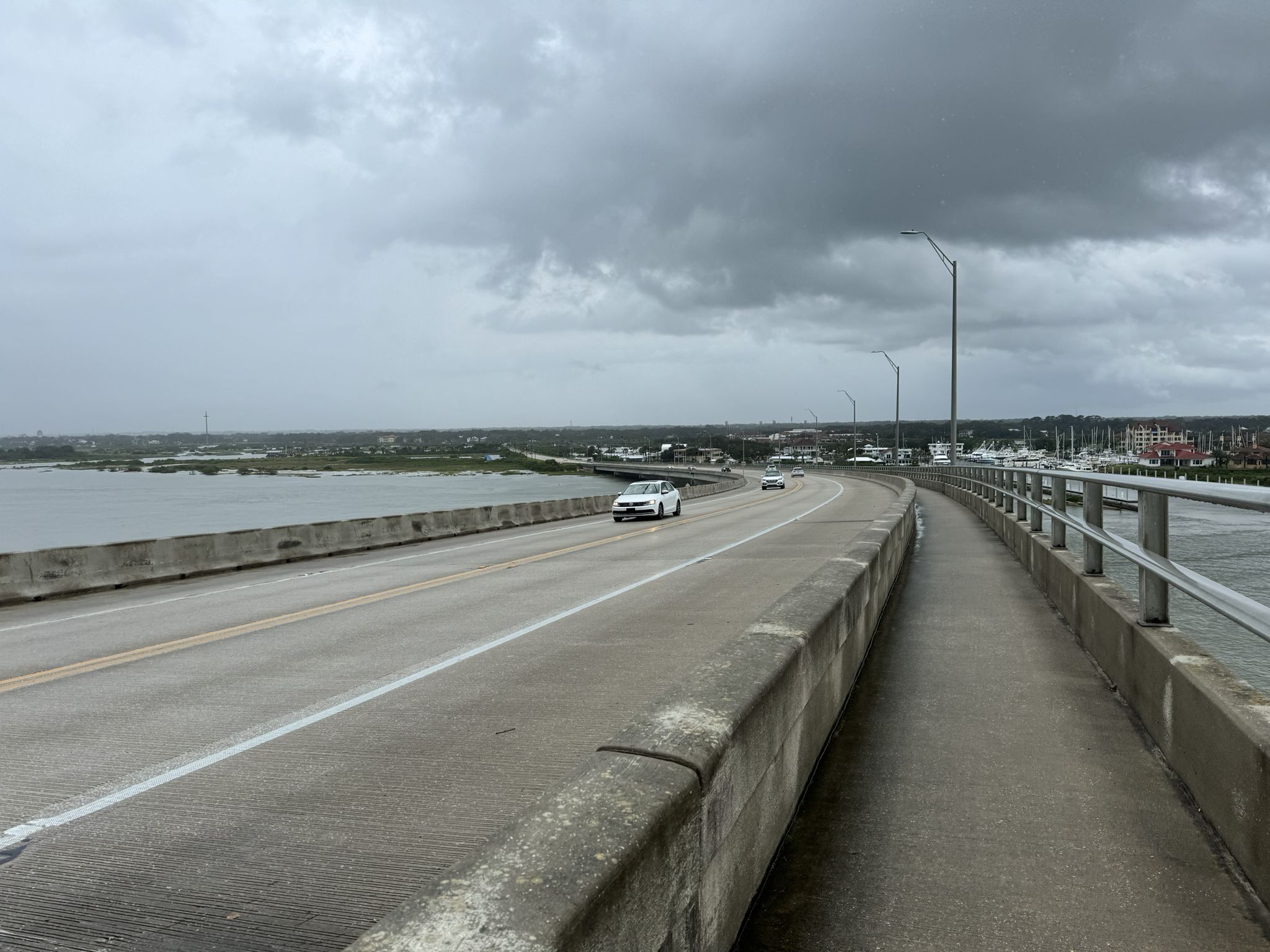 Cars driving on a long bridge over water under a cloudy sky. - East View of Flagler College – St. Augustine Sightseeing Tram loop from Saint Augustine