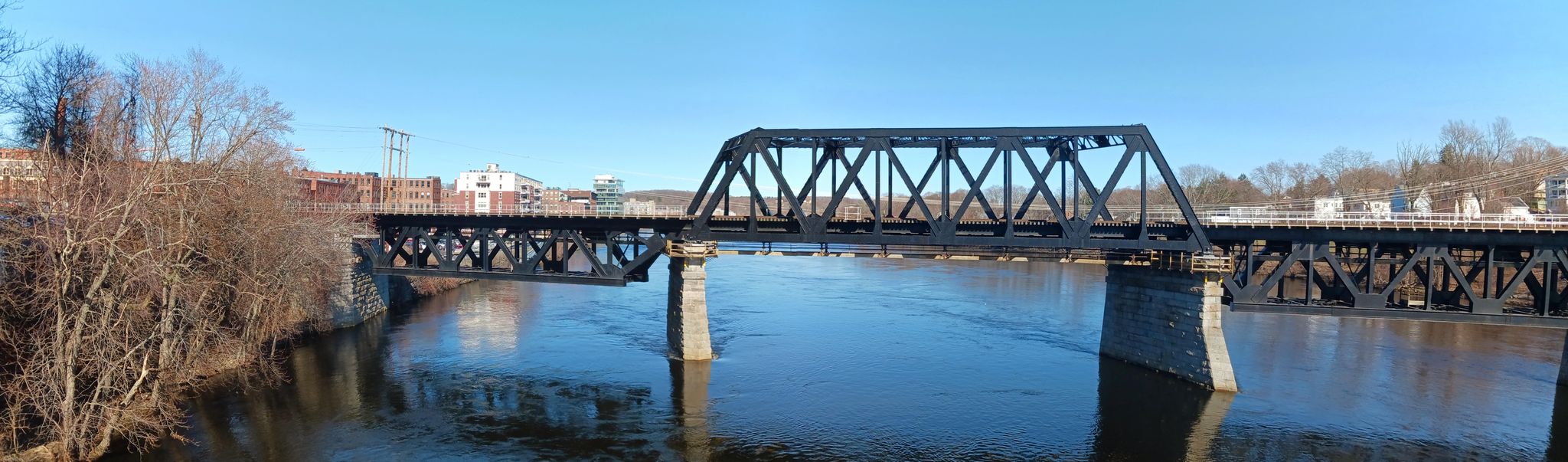 A large metal truss bridge spans a river under a clear blue sky. - Paisley Farm and Greenhouses – Benson’s Ice Cream loop from Lawrence